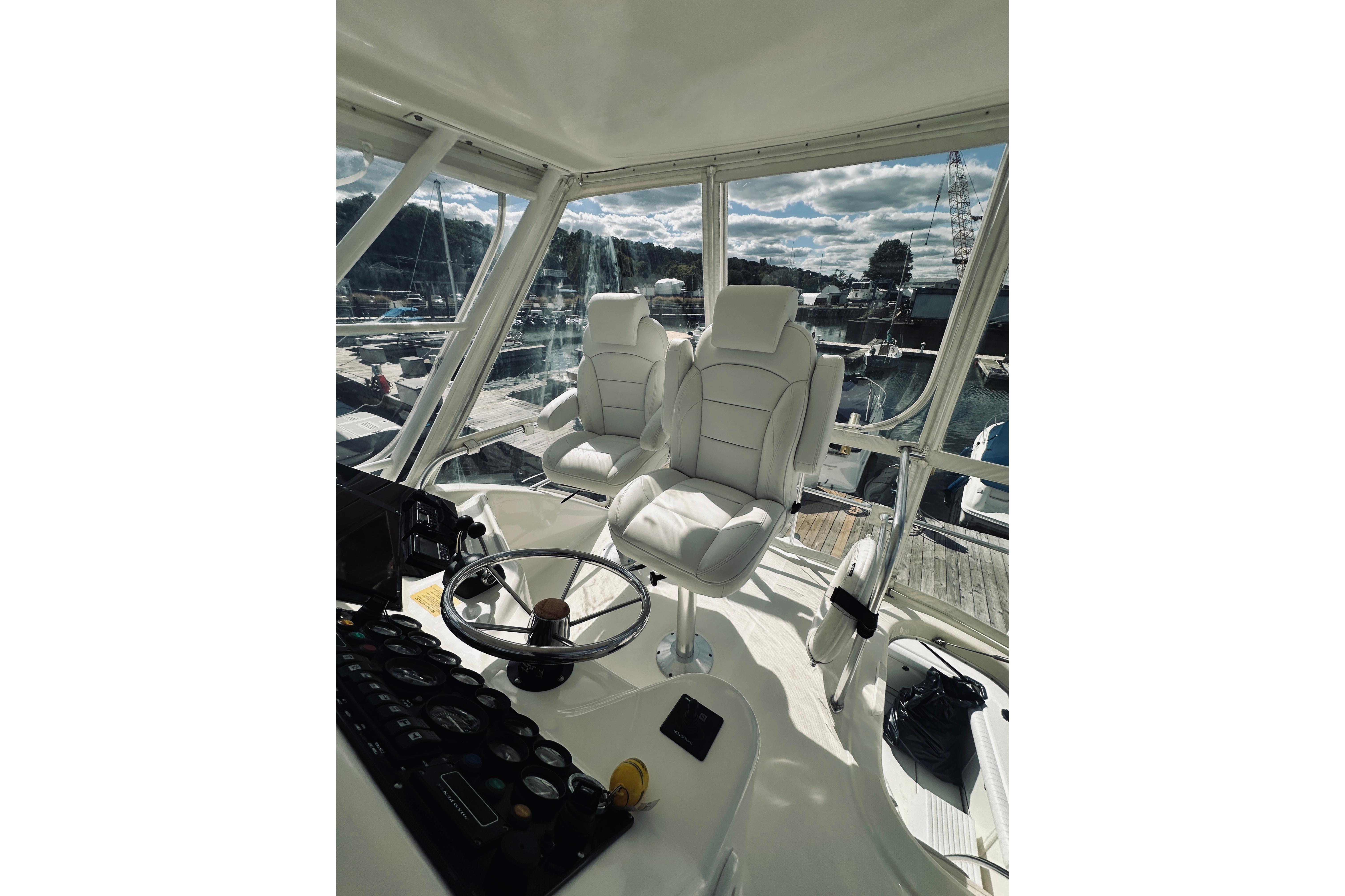 Interior of 2000 Riviera 40 yacht with white captainu0027s chairs and steering wheel.