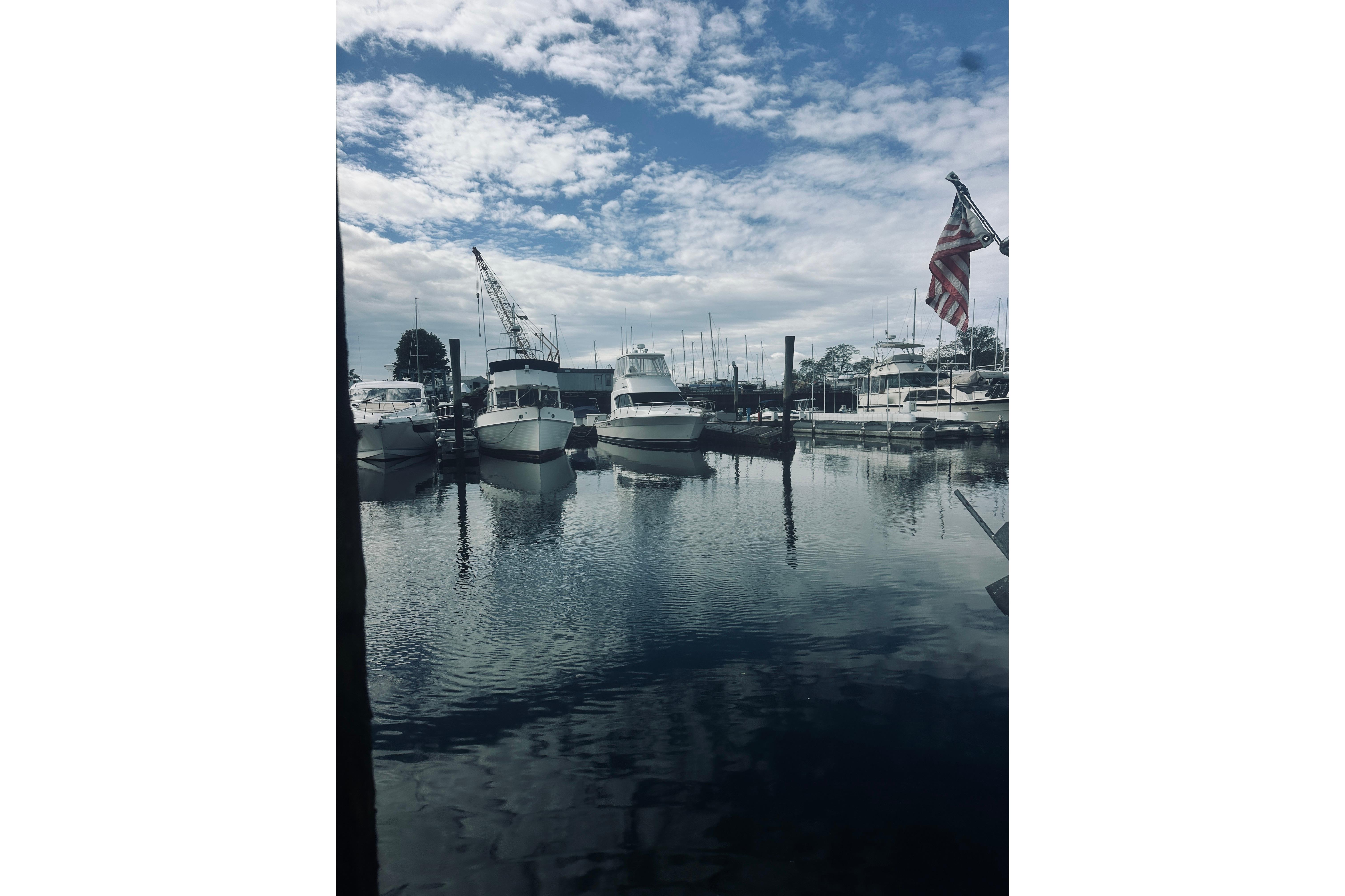 Boats docked at a marina under a cloudy sky, featuring a Riviera 40 from 2000.