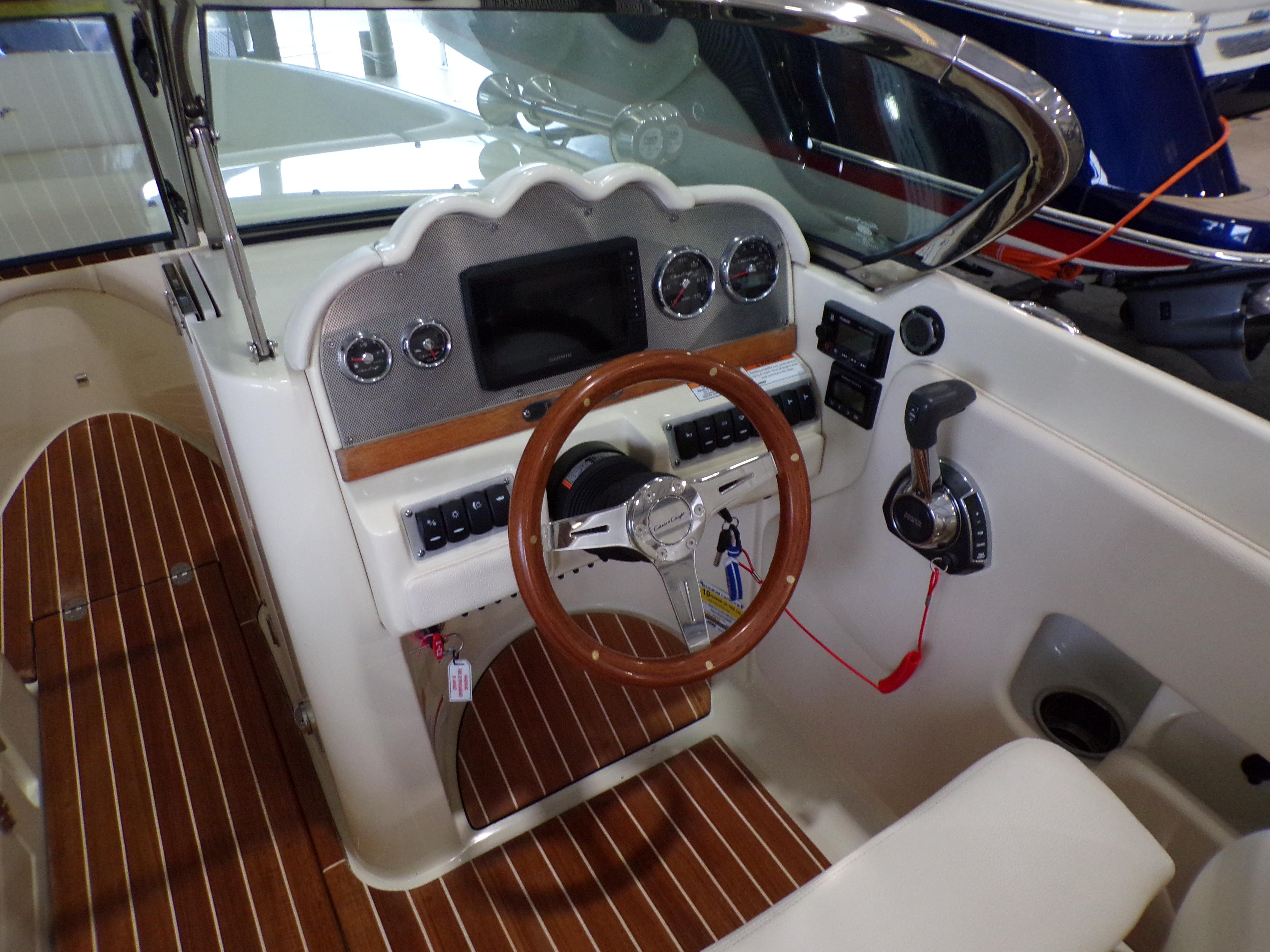 Interior view of 2021 Chris-Craft Launch 27 cockpit with wooden steering wheel.