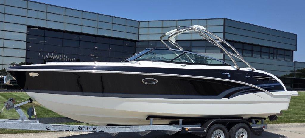 2016 Formula 290 Bowrider boat on trailer, parked outside modern glass building.