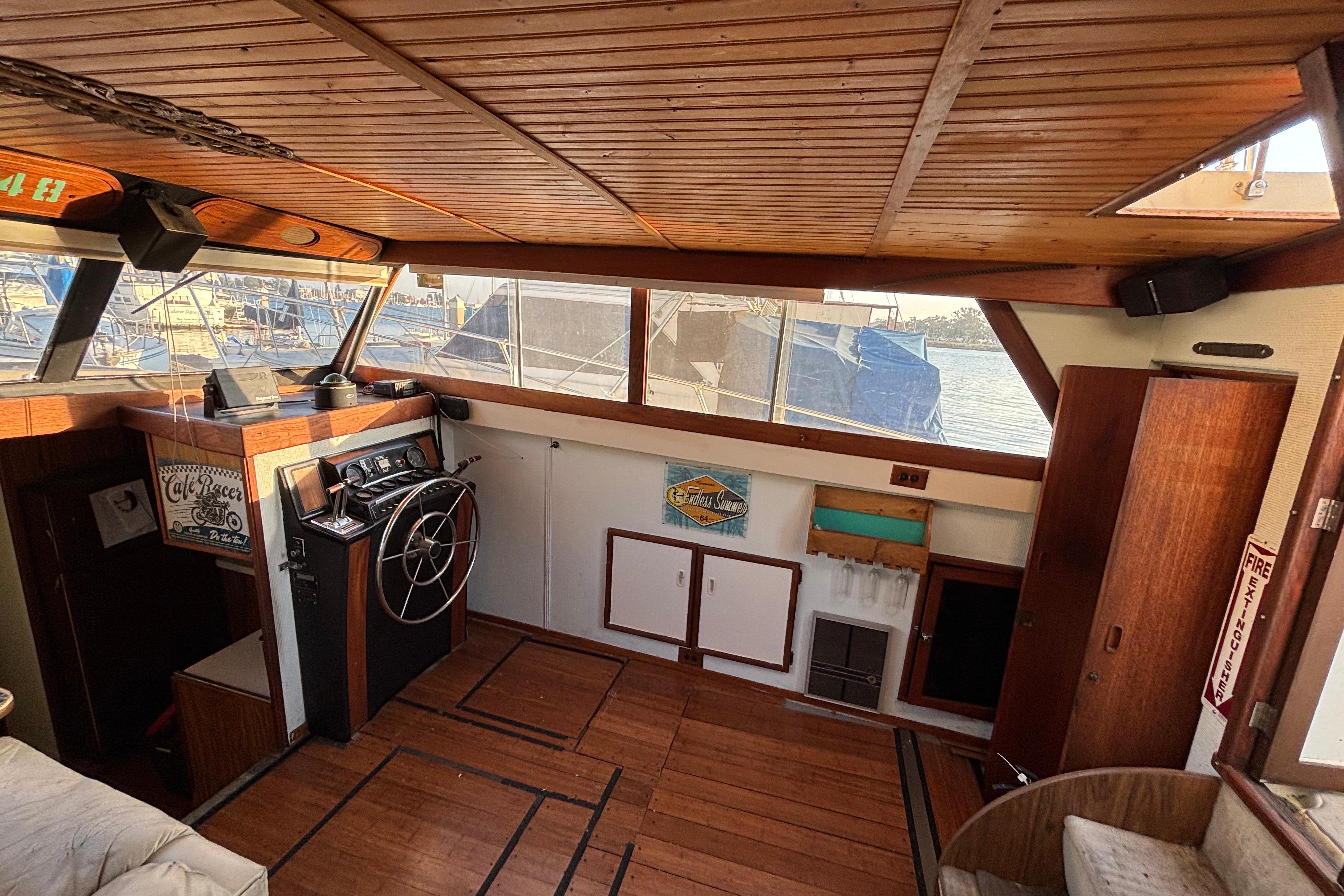 1979 Viking 43 boat interior with wooden paneling and steering wheel, docked at marina.