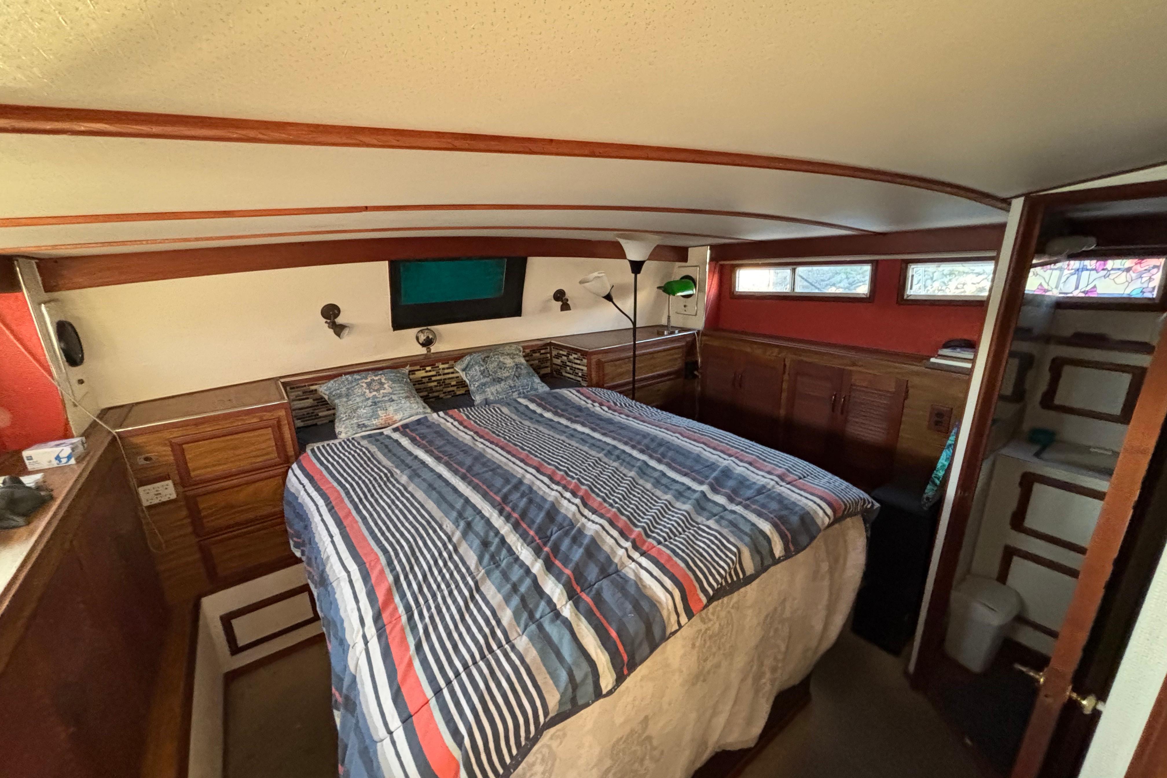 Cozy bedroom interior of a 1979 Viking 43 boat with striped bedding and wooden accents.