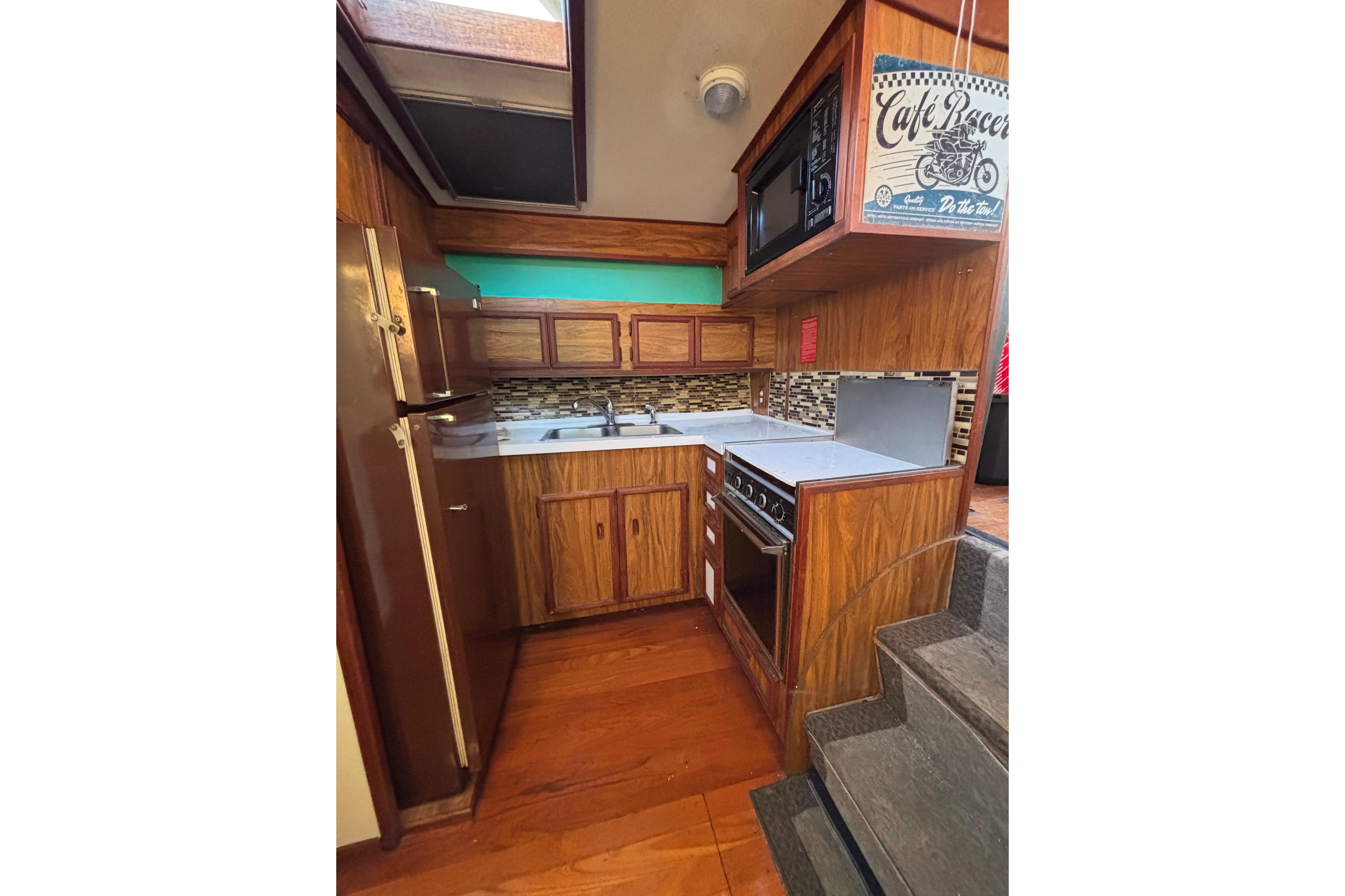 1979 Viking 43 yacht kitchen with wood cabinetry, modern appliances, and mosaic backsplash.