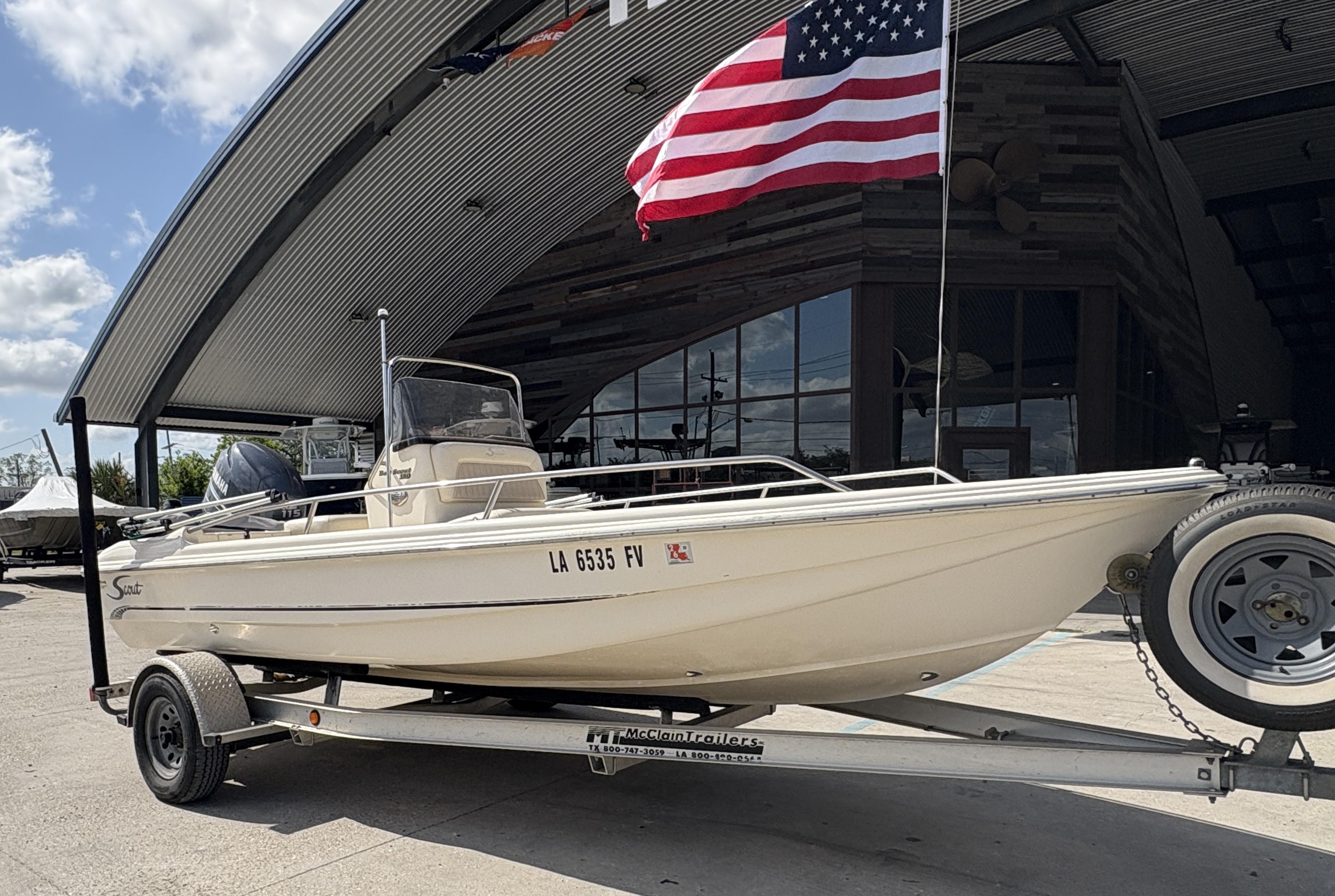 2005 Scout 17 boat on trailer with American flag, parked outside a modern building.