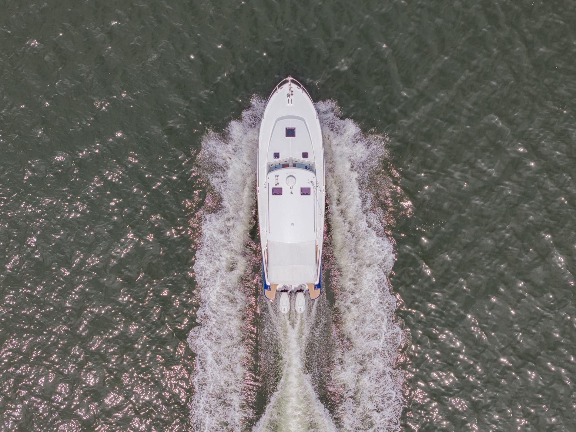 Aerial view of 2025 MJM 35 boat cruising on water, creating a wake.