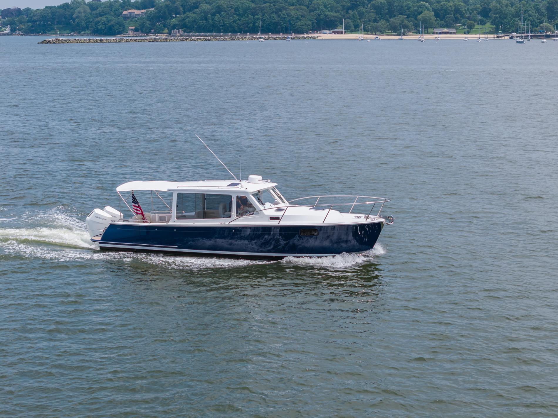 2025 MJM 35 boat cruising on a calm lake with distant shoreline.