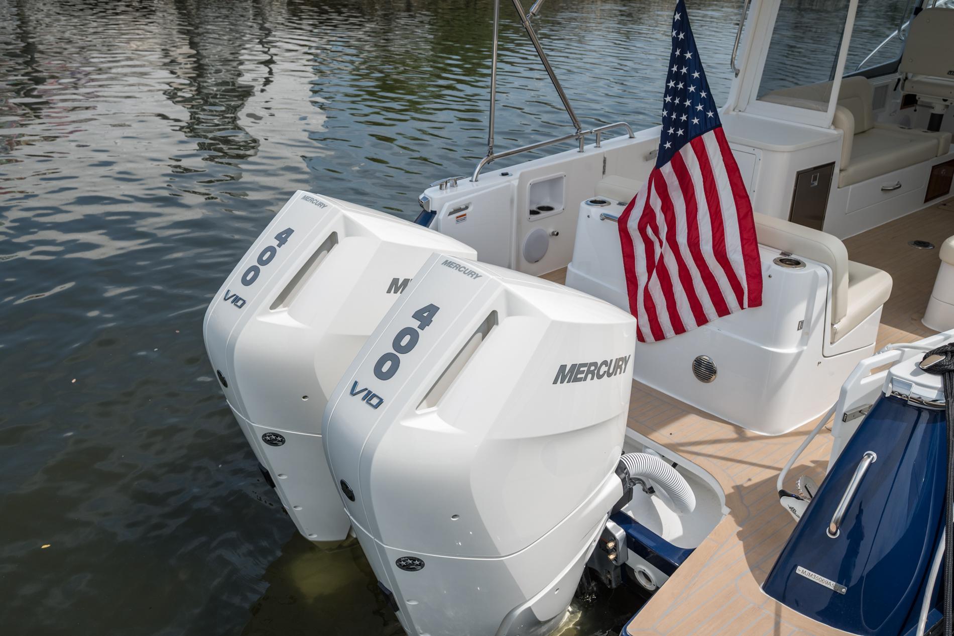 2025 MJM 35 boat with twin Mercury 400 engines and American flag on water.