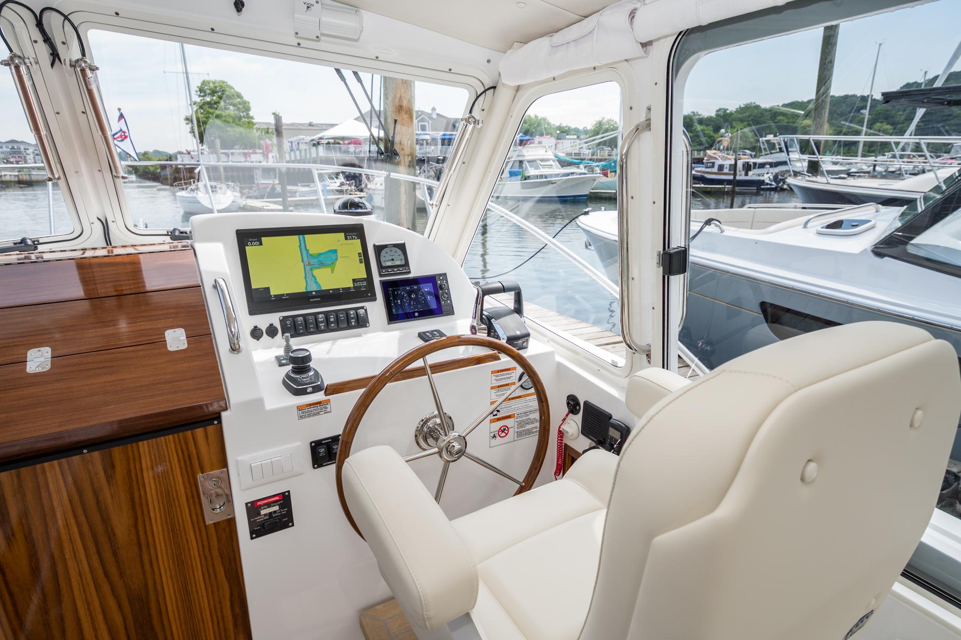 Helm of 2025 MJM 35 boat with navigation screens and wooden steering wheel.