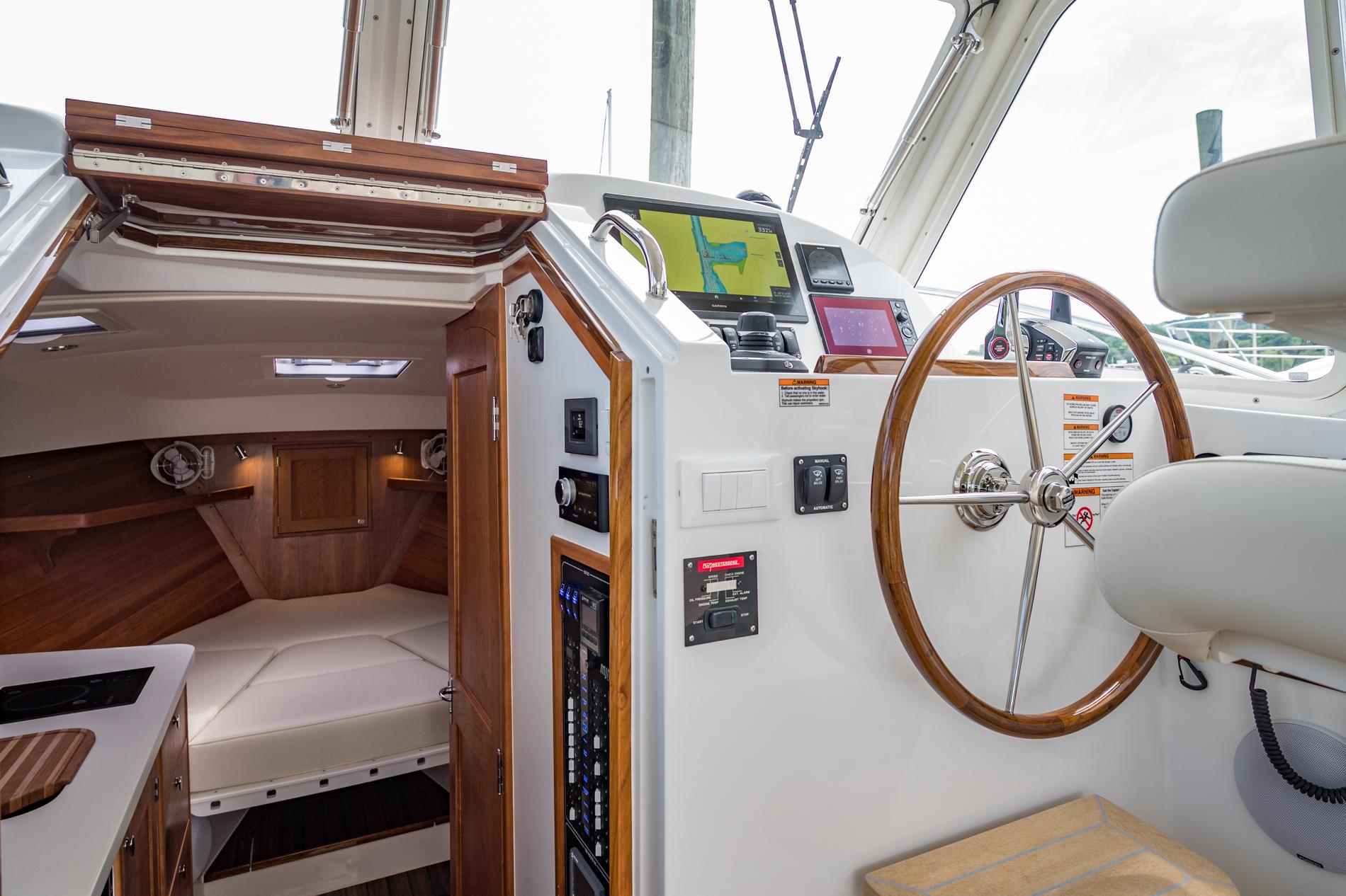 Interior of 2025 MJM 35 boat showing helm, navigation equipment, and cozy cabin.