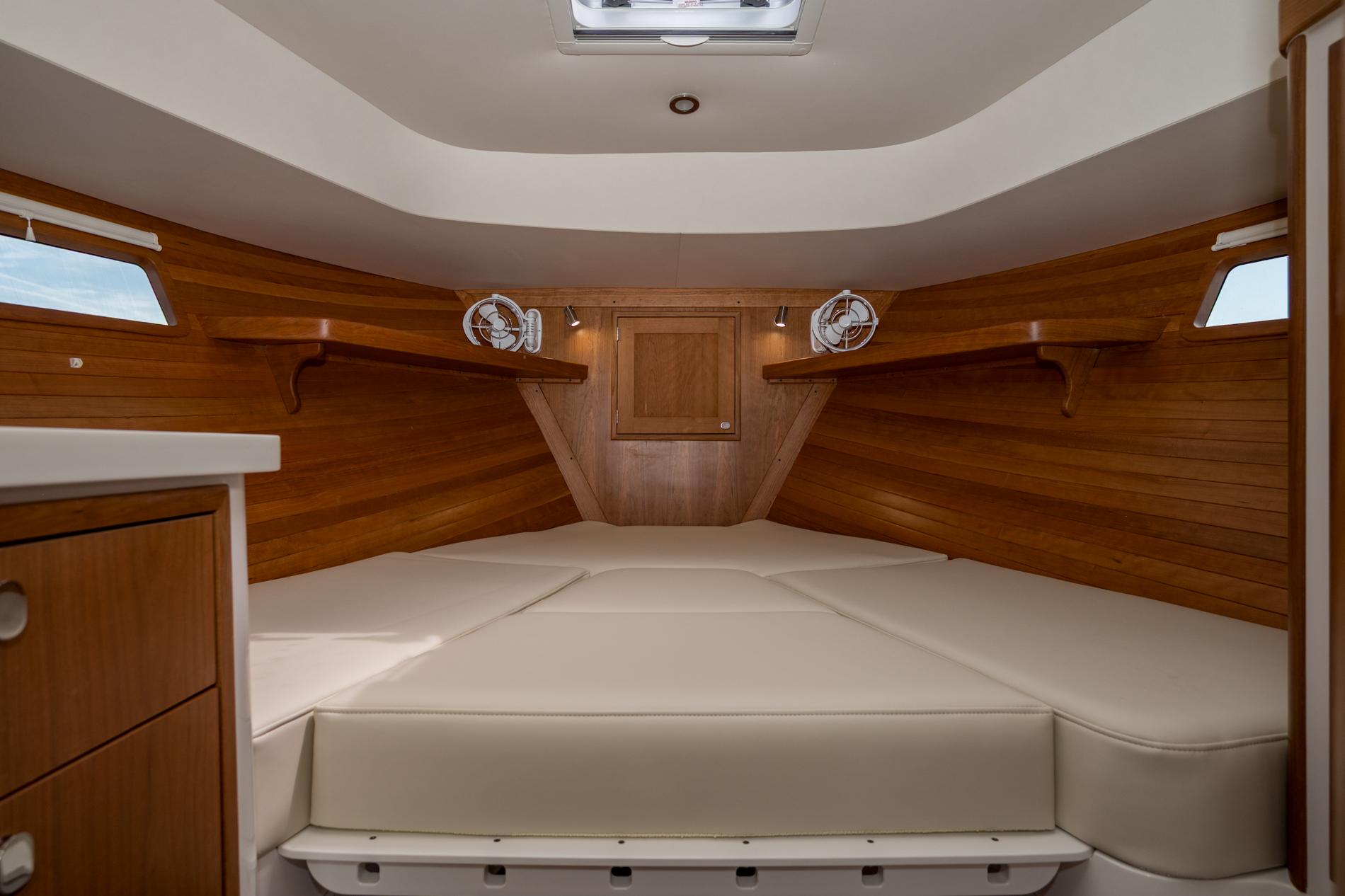 Luxurious cabin interior of 2025 MJM 35 boat with wooden finish and comfortable bedding.
