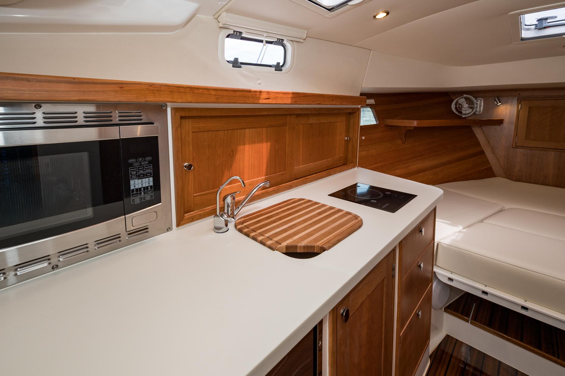 Modern kitchen interior of 2025 MJM 35 boat with microwave, sink, and stove.