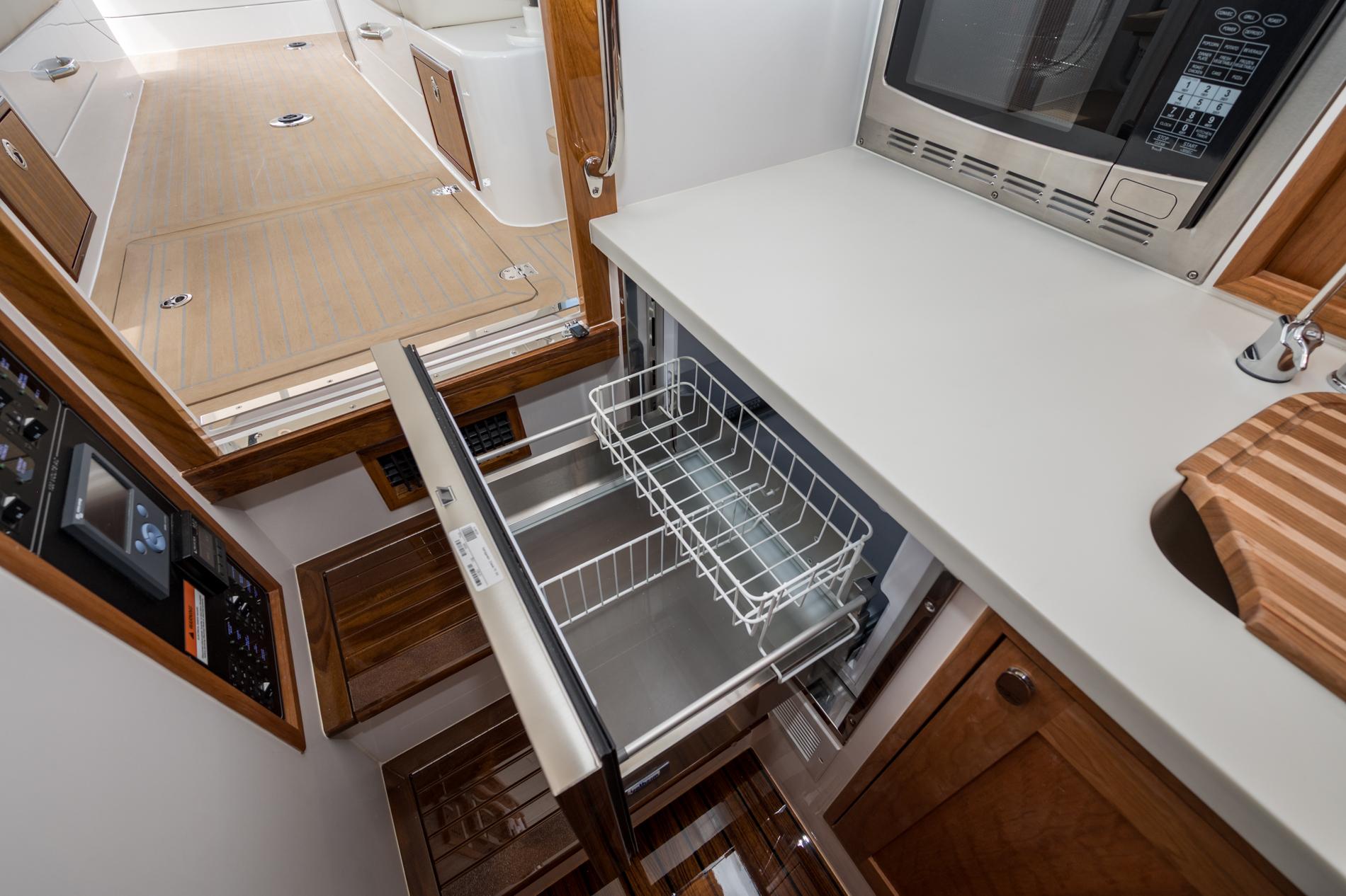 Modern MJM 35 yacht interior with open drawer, microwave, and wooden cabinetry, 2025 model.