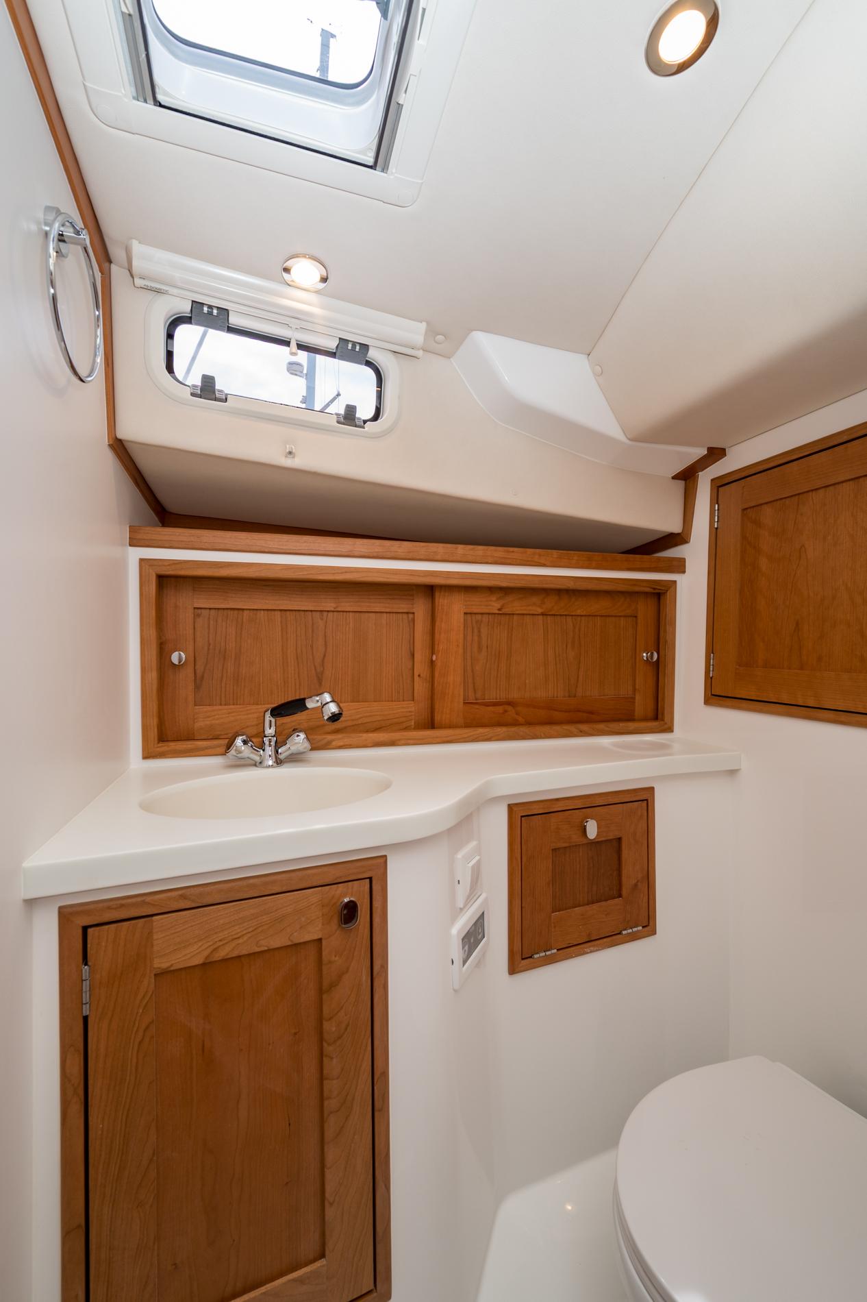 Modern bathroom interior in 2025 MJM 35 boat, featuring wood cabinetry and sleek fixtures.