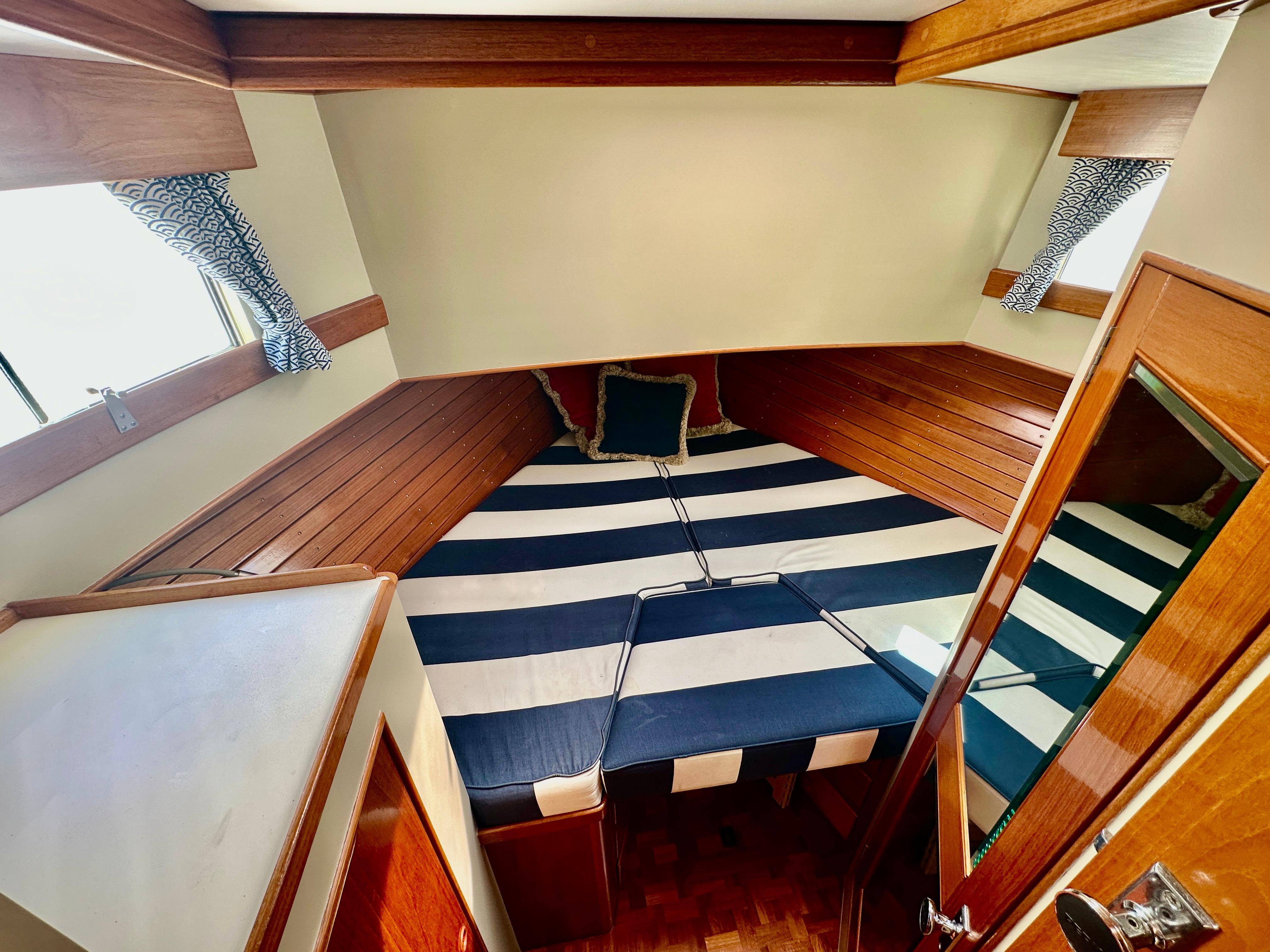 1989 Grand Banks 42 Classic cabin with striped bedding and wooden interior.