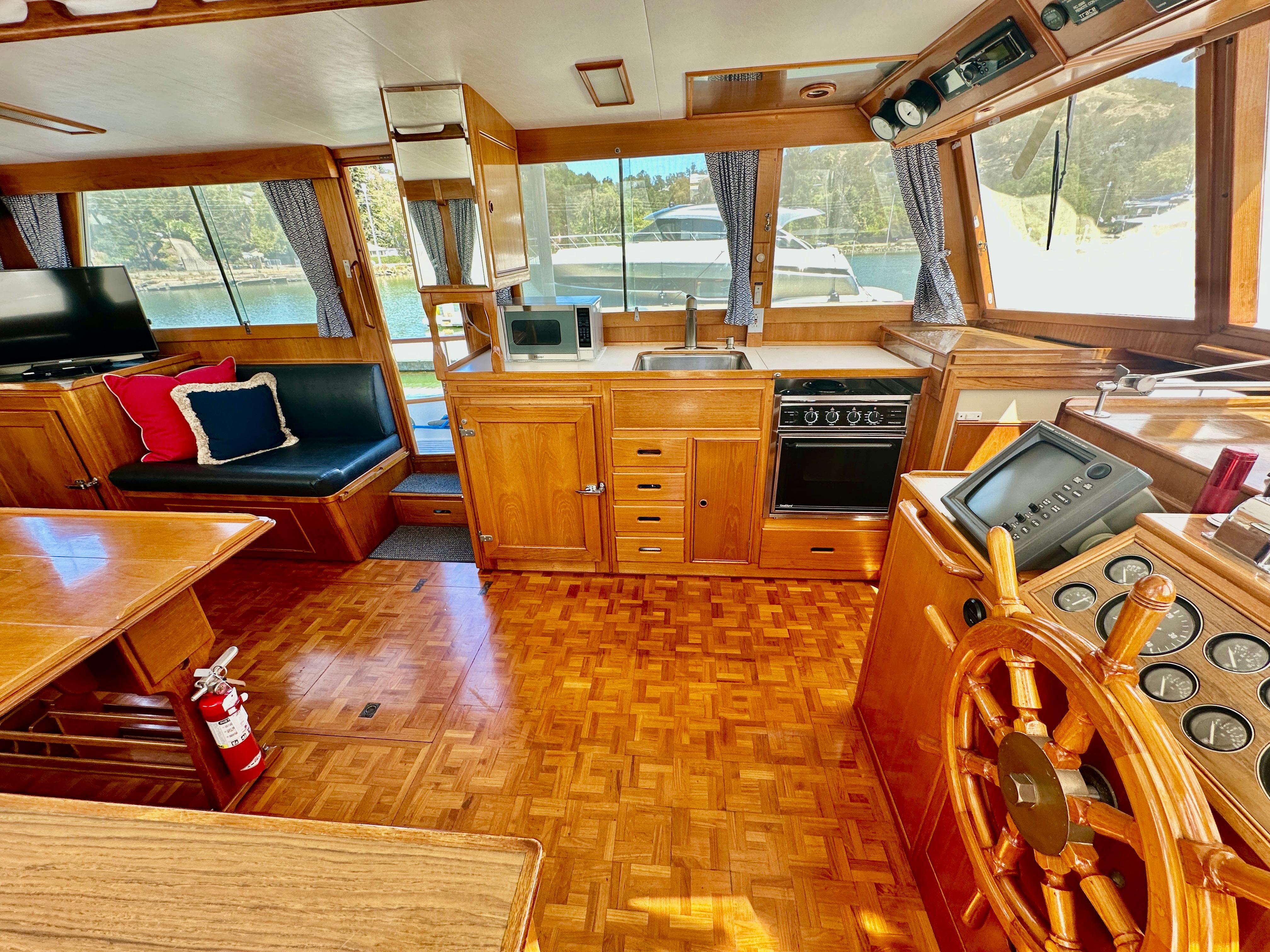 Interior of 1989 Grand Banks 42 Classic yacht with wooden helm, kitchen, and seating area.
