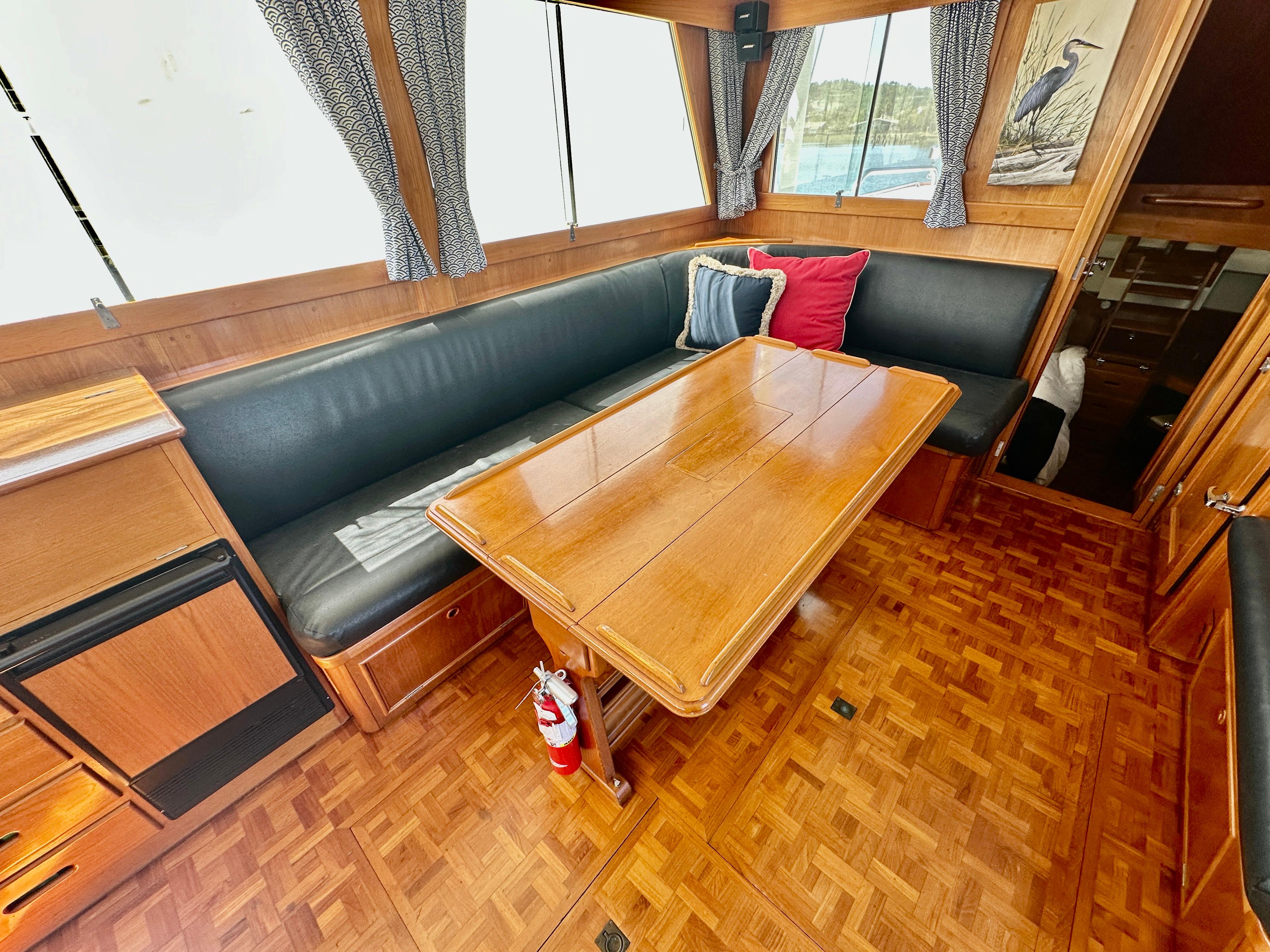 1989 Grand Banks 42 Classic interior with wooden table, cushioned seating, and decorative pillows.