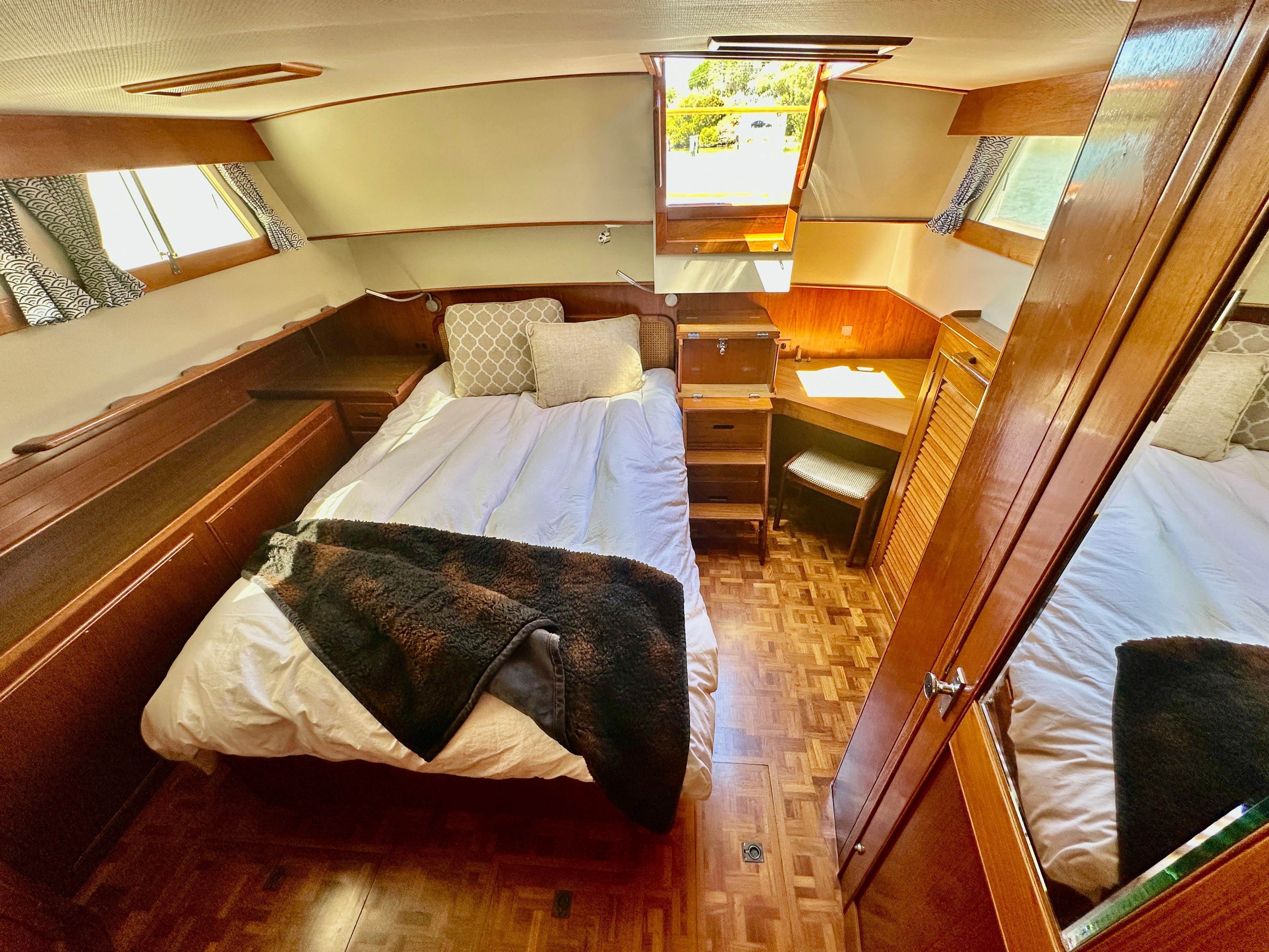 Cozy bedroom in 1989 Grand Banks 42 Classic yacht with wood accents and natural light.
