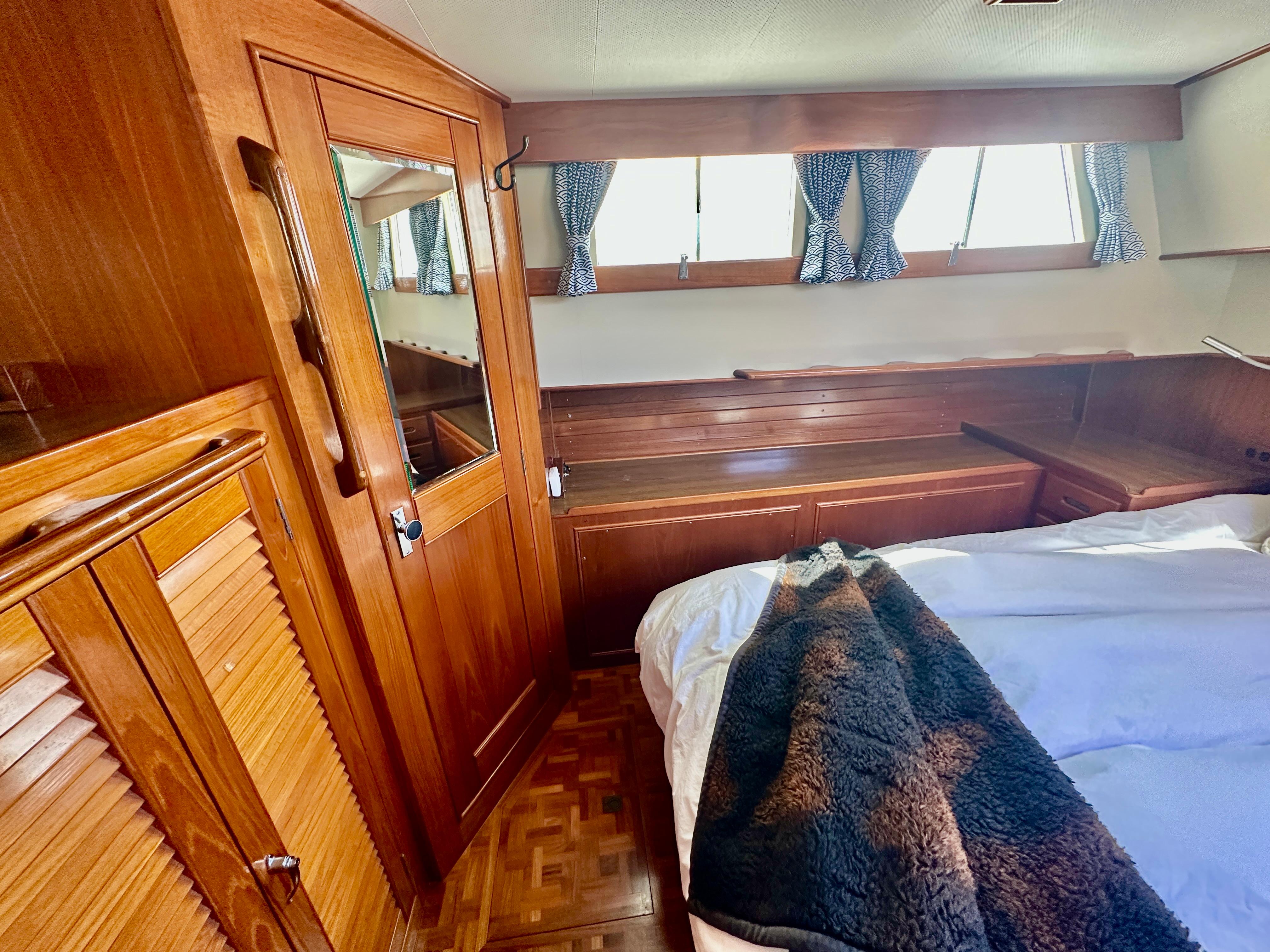 Cozy cabin interior of 1989 Grand Banks 42 Classic with wood paneling and bed.