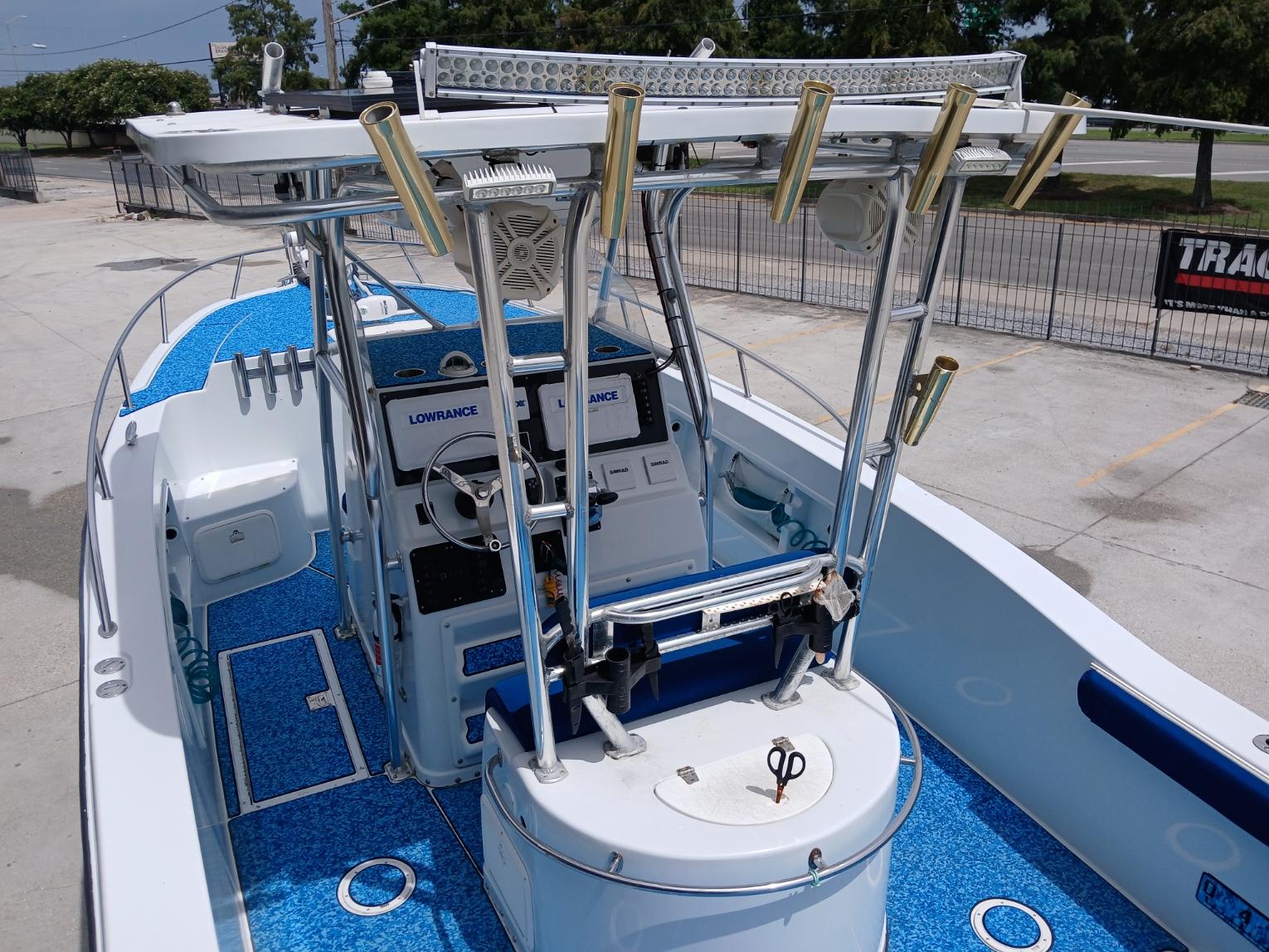 2002 ProKat 2860 Center Console boat with blue deck, fishing rod holders, and navigation equipment.