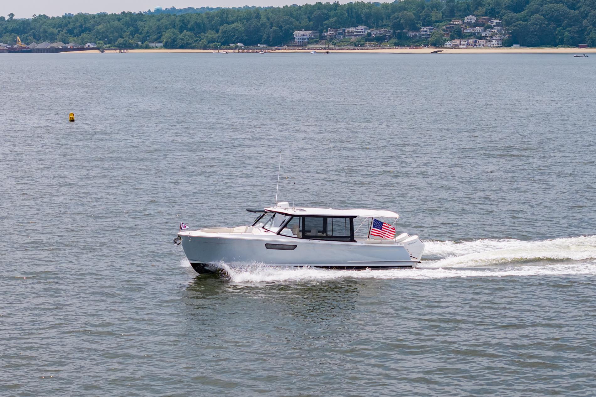 2025 MJM 3 boat cruising on a calm lake with scenic shoreline.