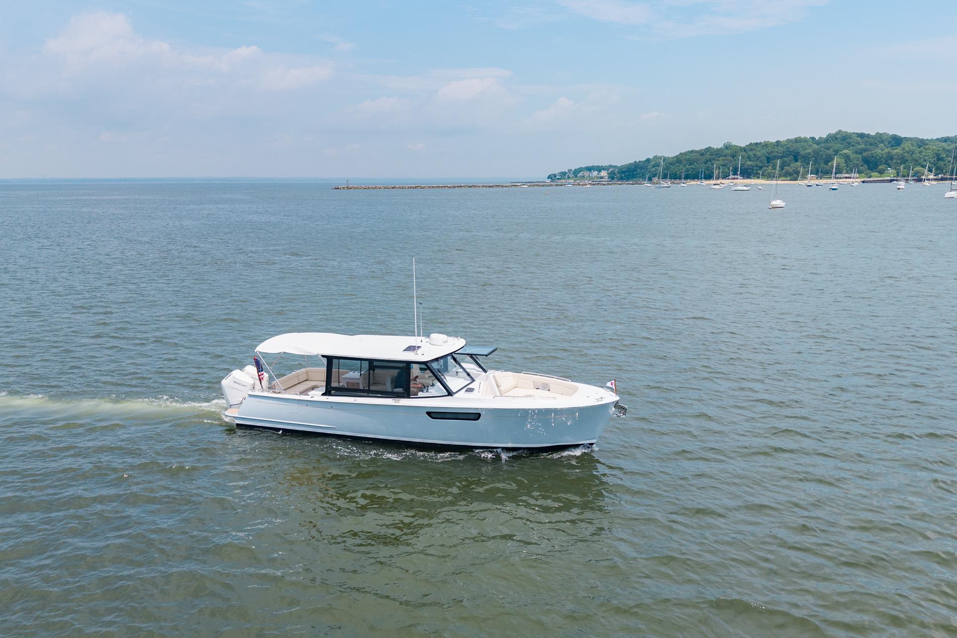 2025 MJM 3 boat cruising on a calm sea near a scenic coastline.