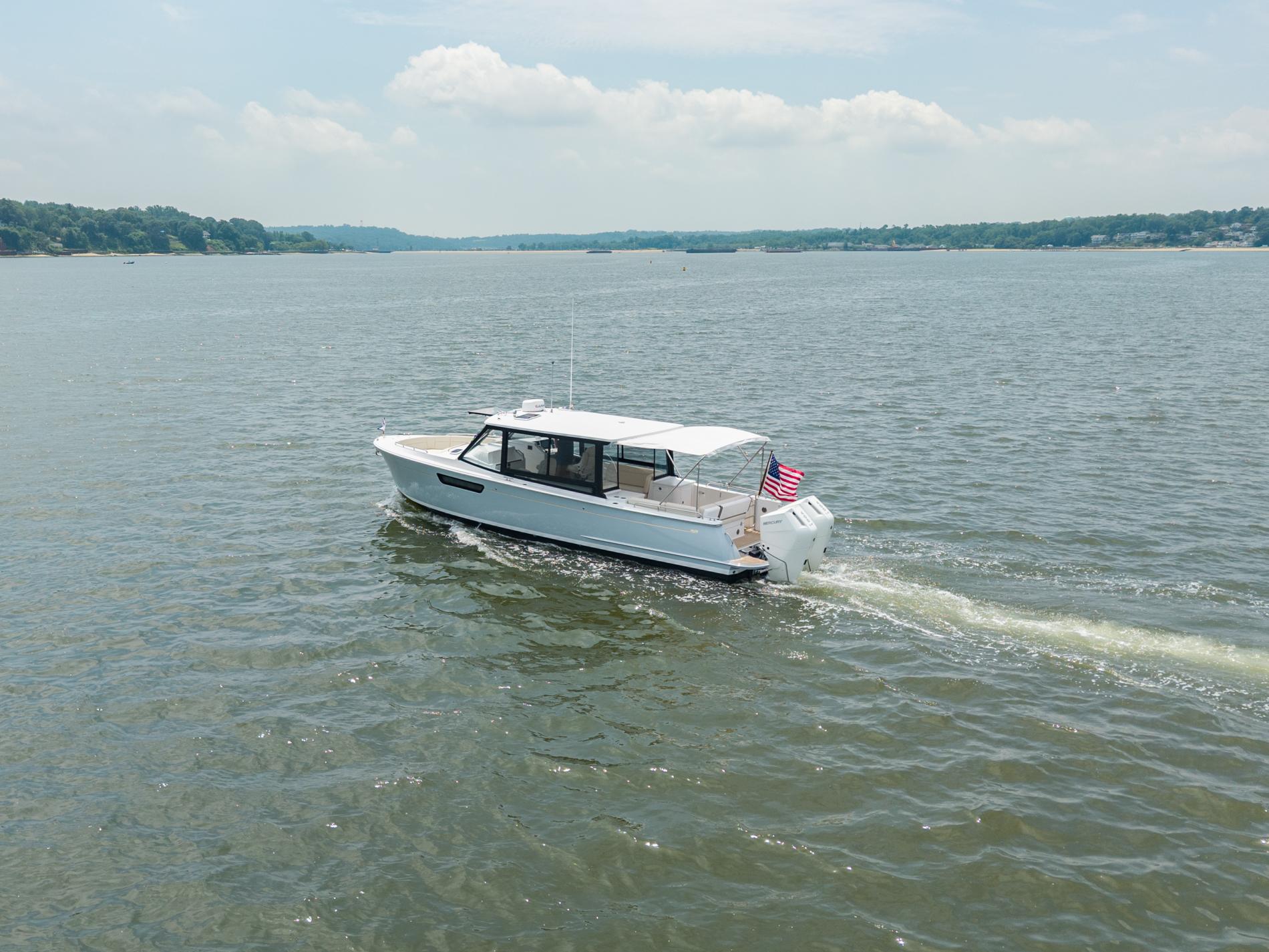 2025 MJM 3 boat cruising on a calm lake with an American flag.
