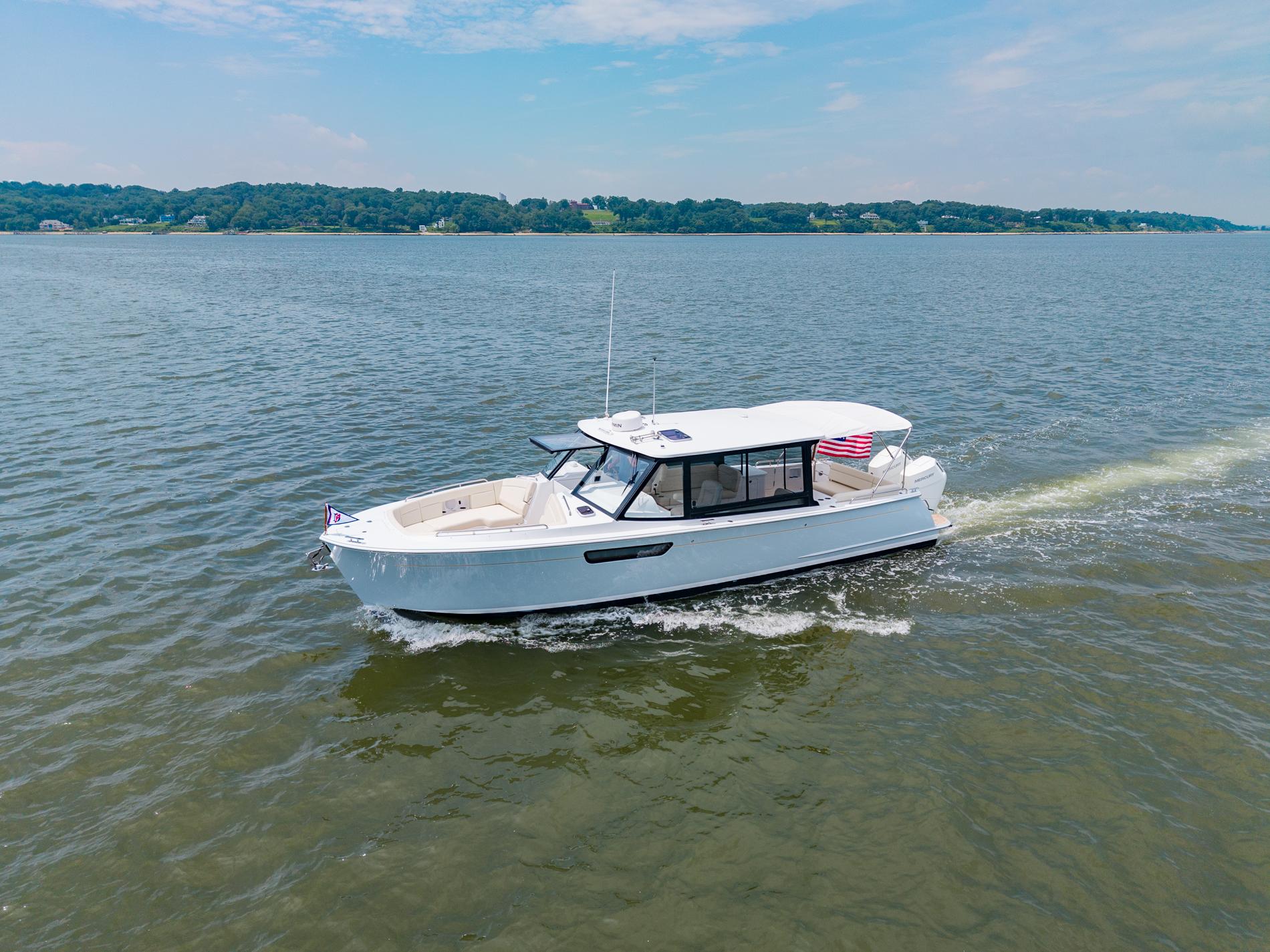 2025 MJM 3 boat cruising on a lake under a clear blue sky.