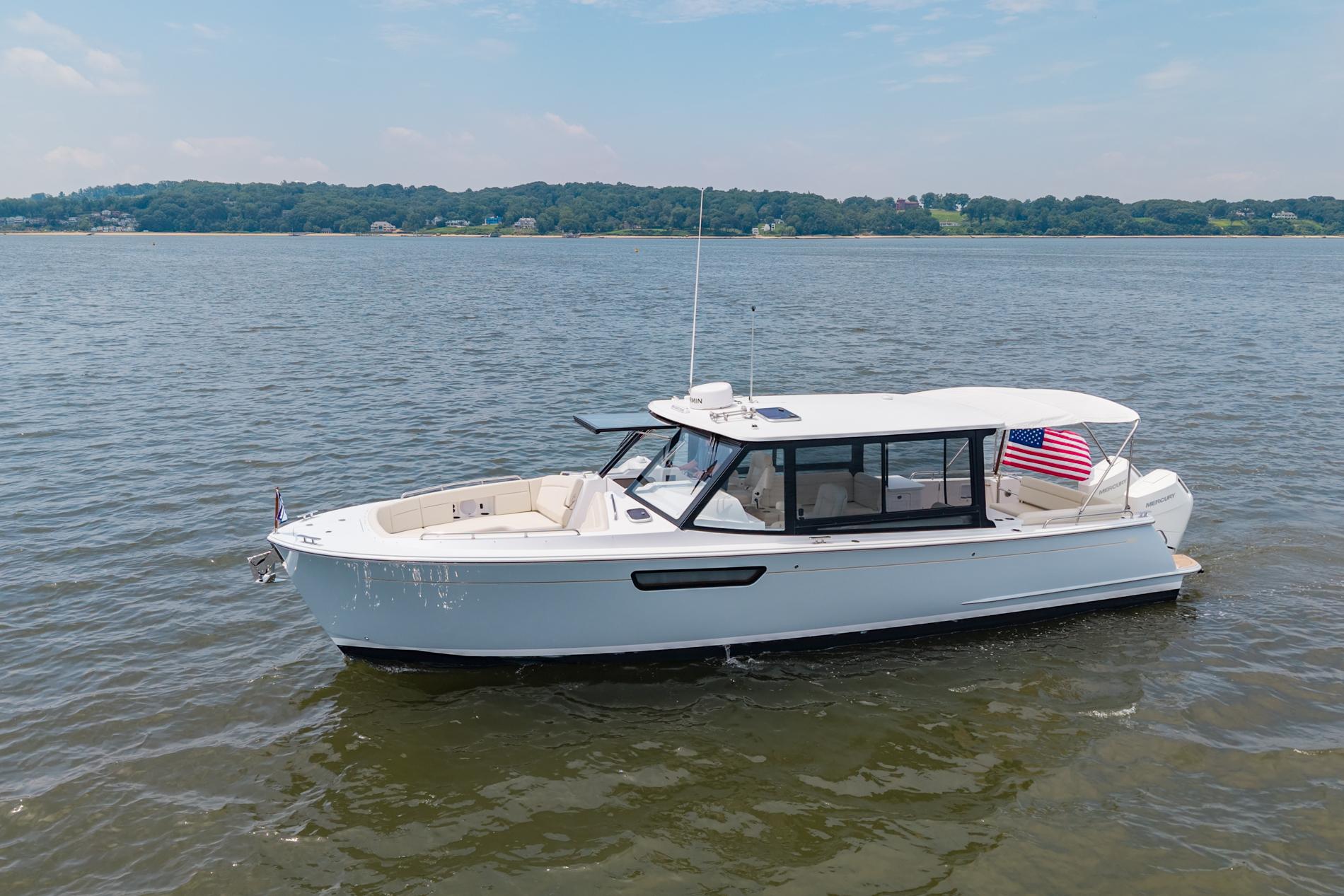 2025 MJM 3 boat on calm water with American flag, clear sky background.
