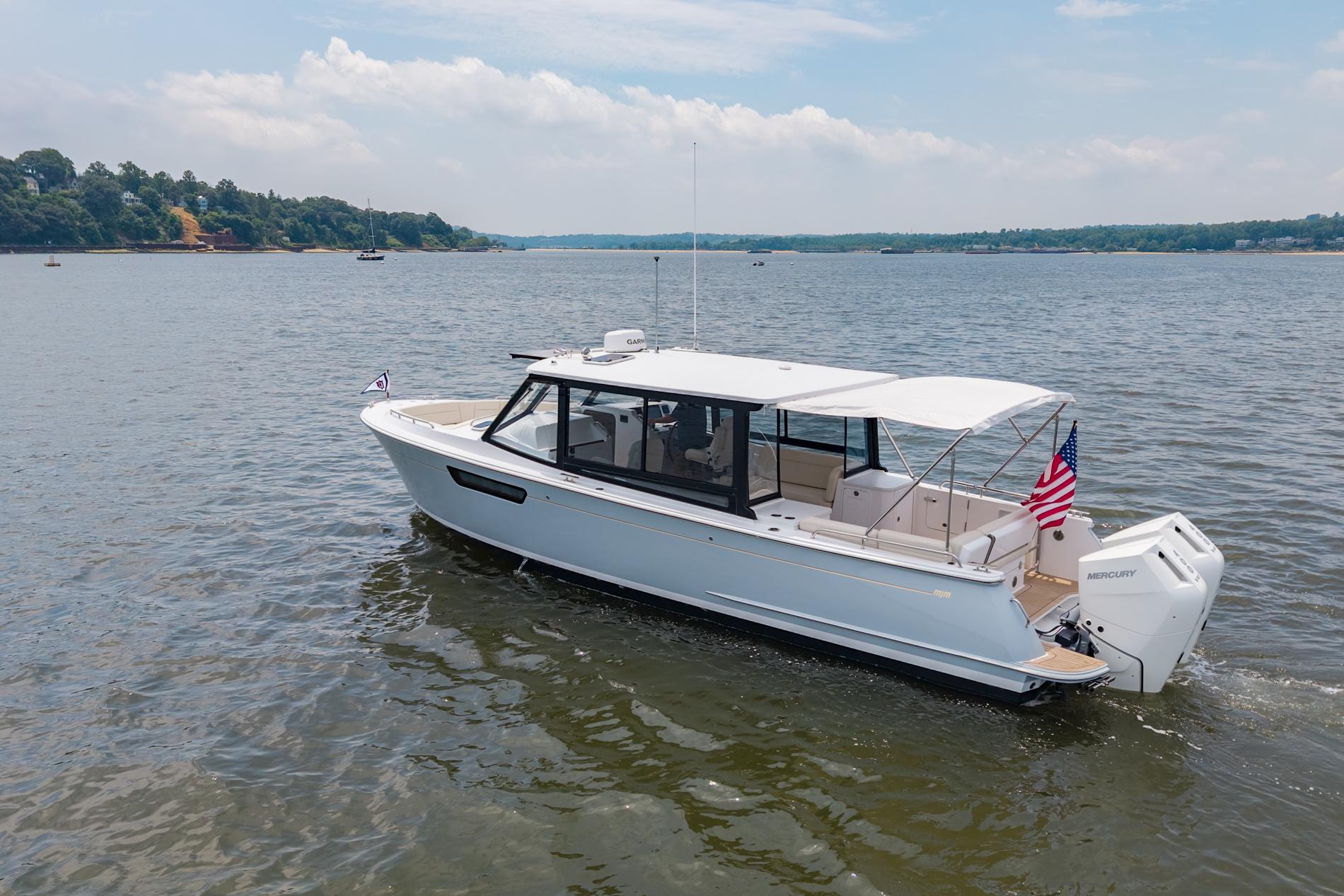 2025 MJM 3 boat cruising on a calm lake with scenic shoreline.
