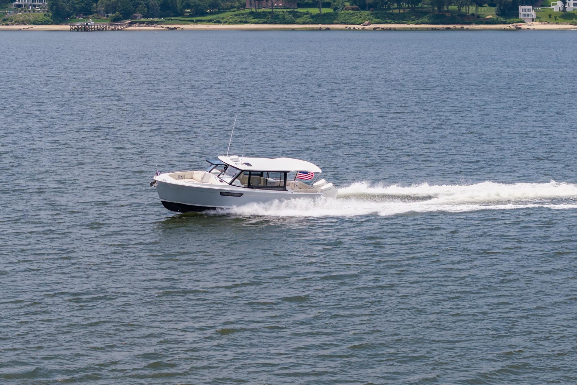 2025 MJM 3 boat cruising on a calm lake with shoreline in the background.