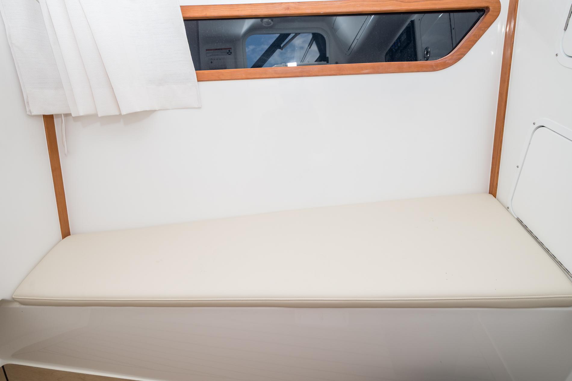 Interior of 2025 MJM 3 boat with cushioned seating and window.