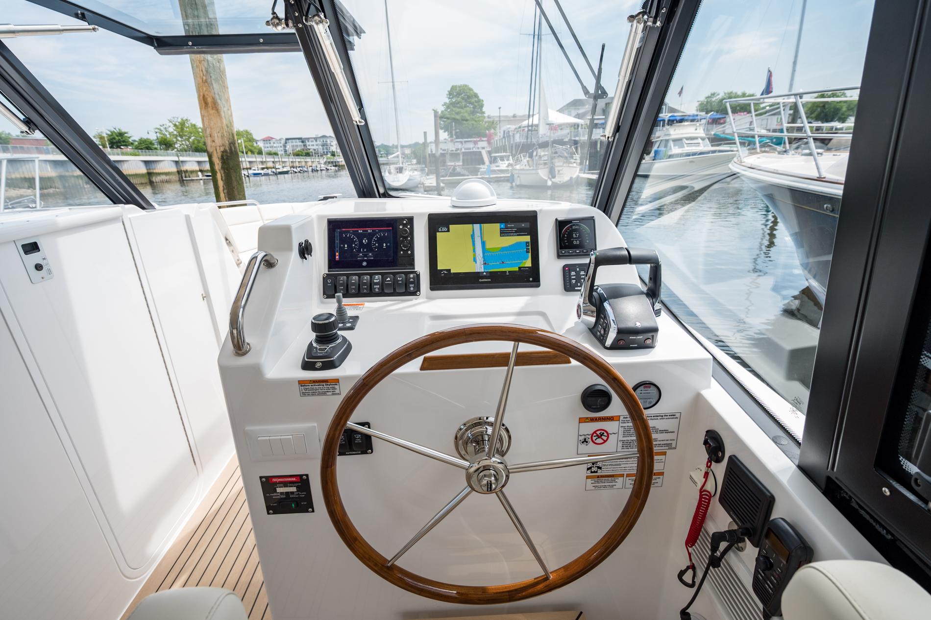 Helm of 2025 MJM 3 boat with navigation screens and wooden steering wheel.
