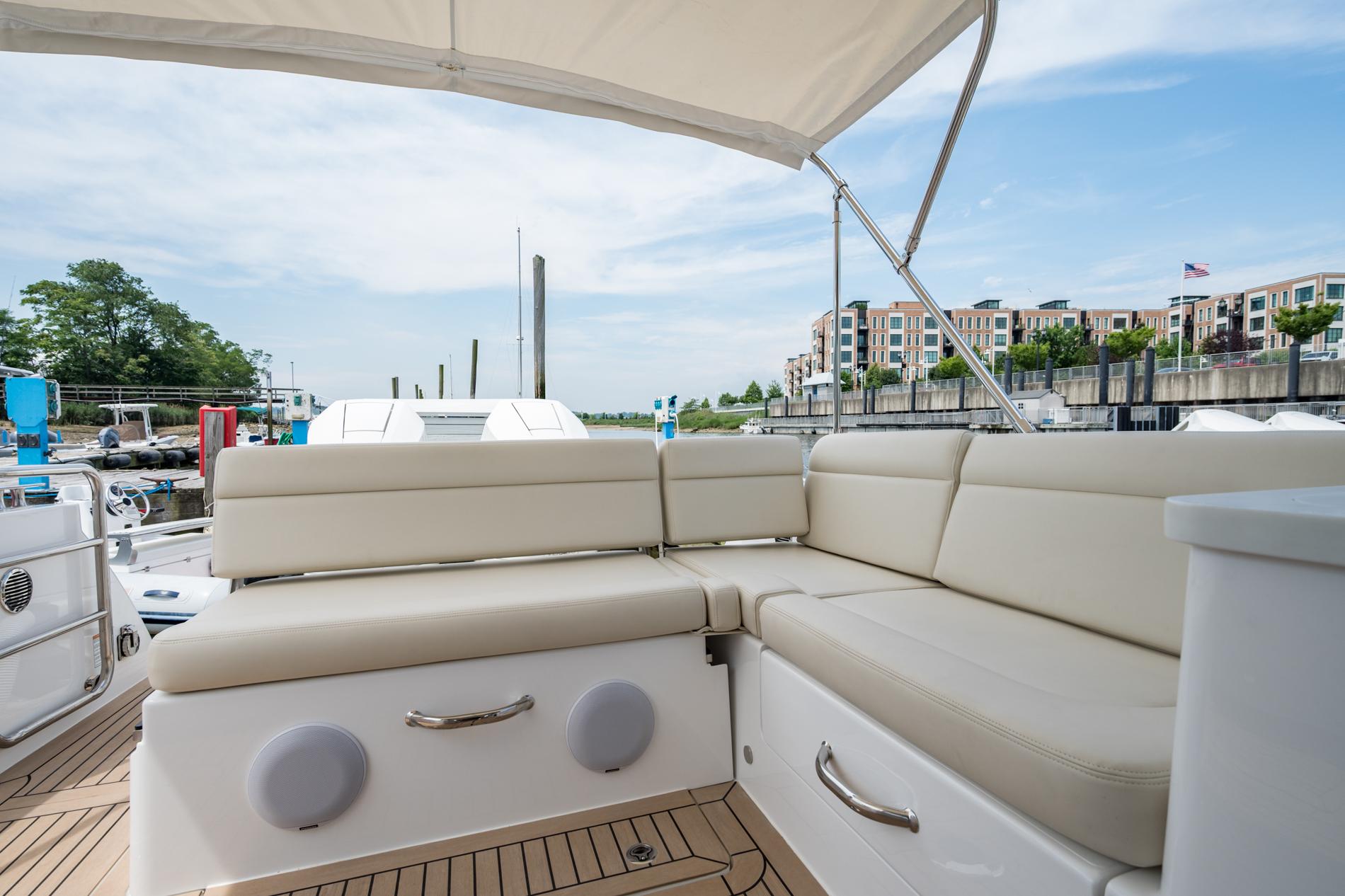 Luxurious seating area on 2025 MJM 3 yacht, docked with scenic waterfront view.