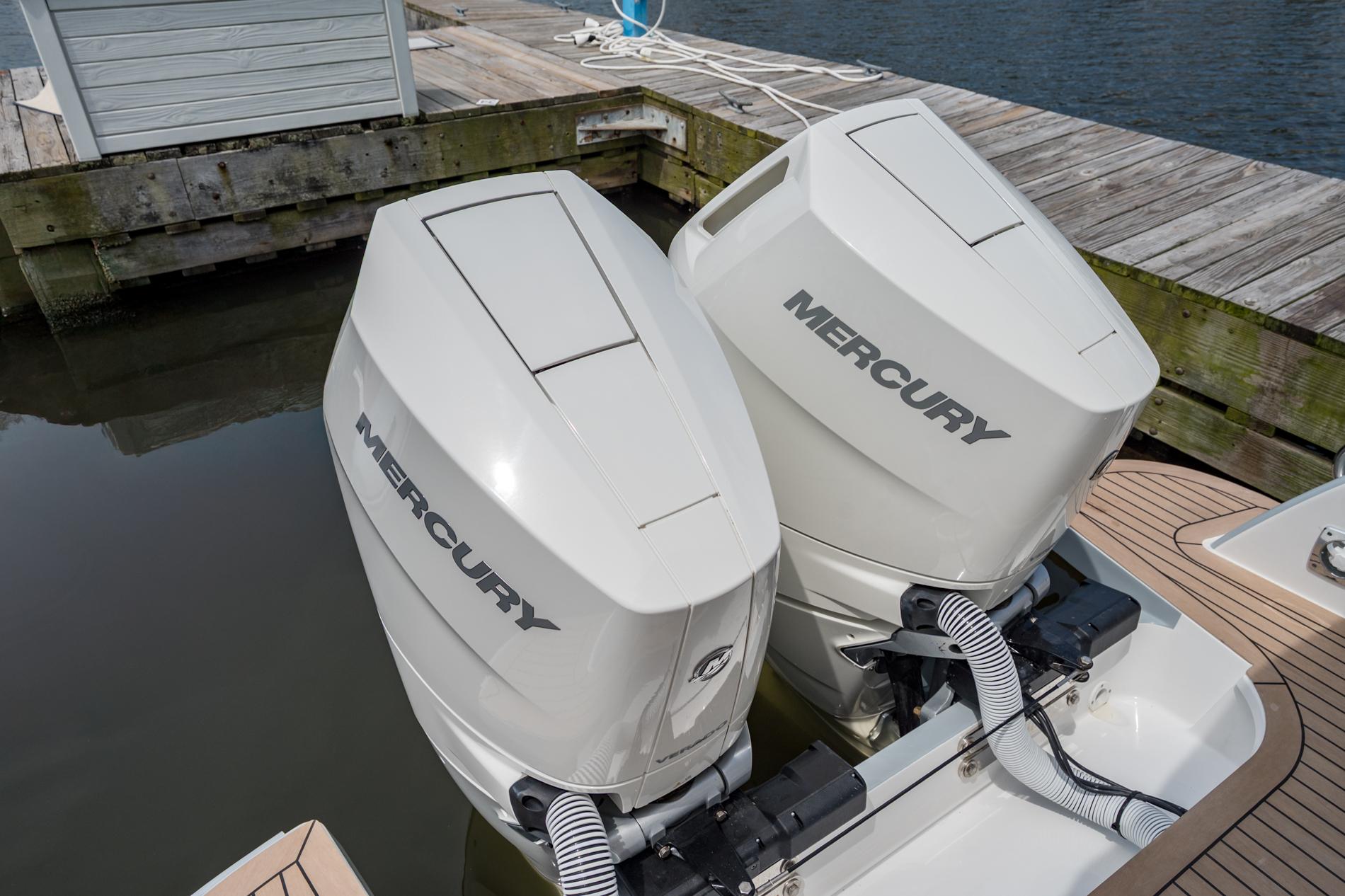 Twin Mercury outboard engines on a 2025 MJM 3 boat docked by the water.