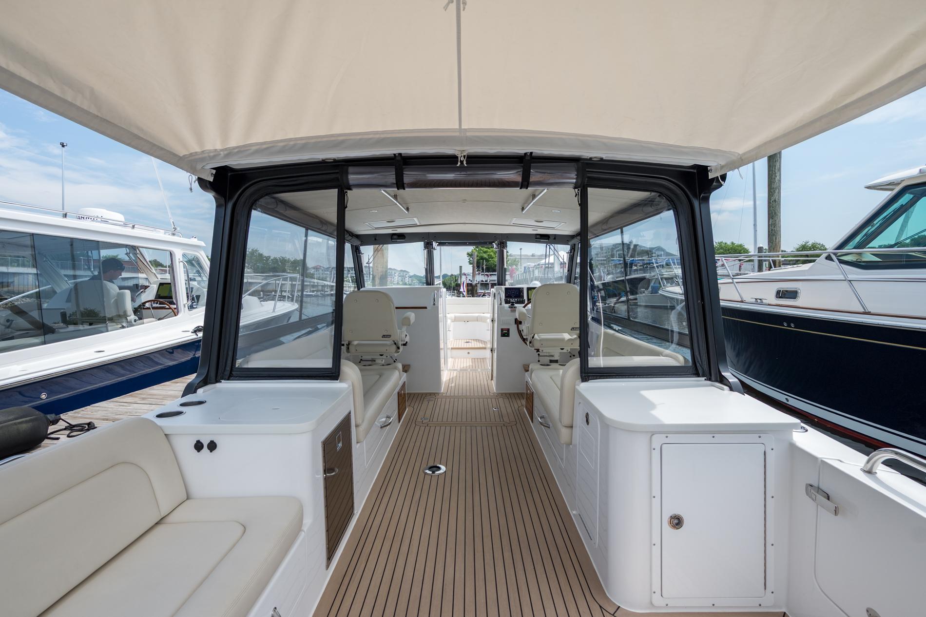 2025 MJM 3 boat interior with seating, helm, and canopy in marina setting.