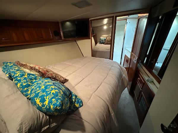 Cozy bedroom in 1988 Buddy Davis Convertible yacht with plush bedding and wooden accents.