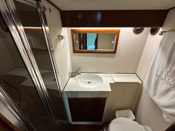 Compact bathroom in a 1988 Buddy Davis Convertible yacht, featuring a sink, mirror, and shower.