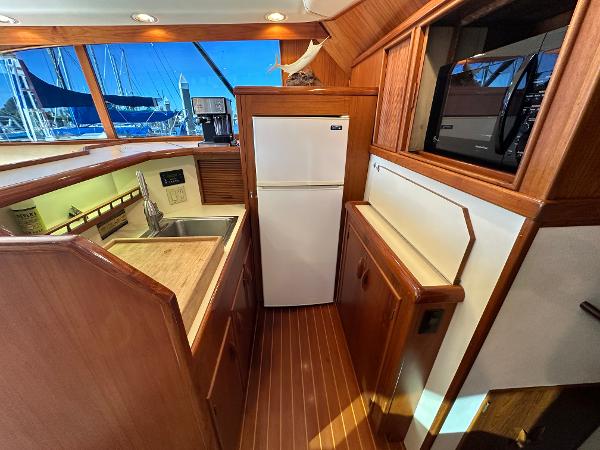 1988 Buddy Davis Convertible yacht kitchen with wood finish, sink, and refrigerator.