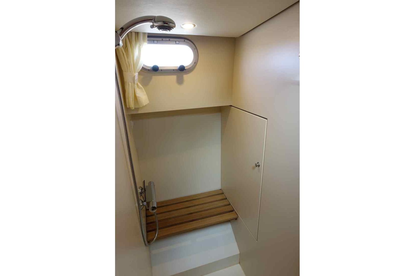 Shower area in 2014 Linssen Grand Sturdy 40.9 AC yacht with wooden bench and porthole.