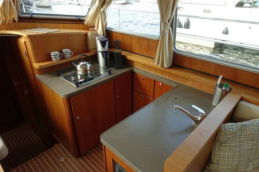 Cozy kitchen area in 2014 Linssen Grand Sturdy 40.9 AC yacht with wooden cabinetry.