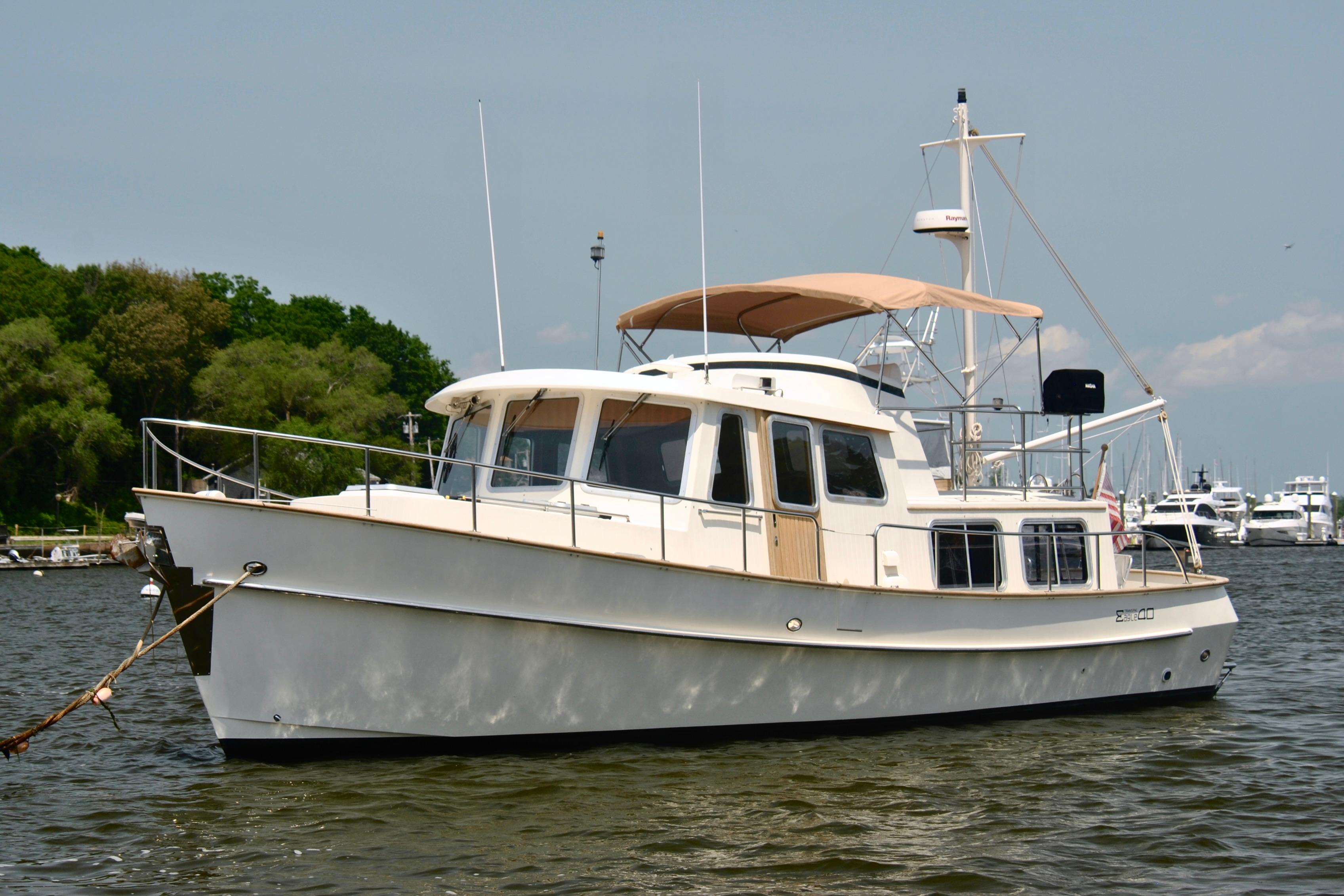2004 Transpacific Marine Eagle 40 yacht anchored on calm water, with lush greenery in the background.