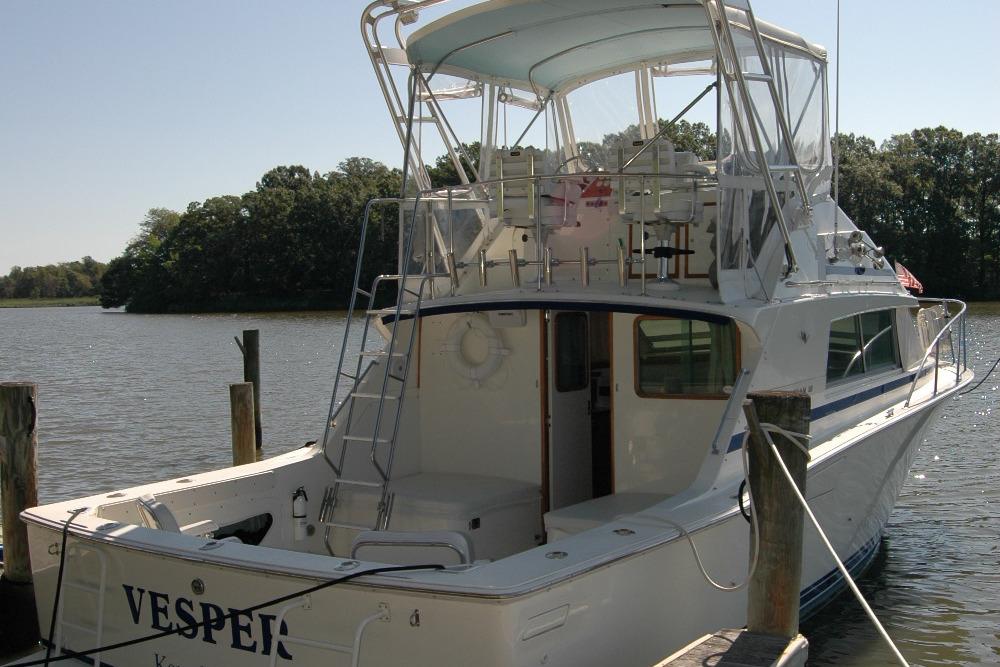 1987 Bertram 33 Sport Fisherman docked by a serene lake.