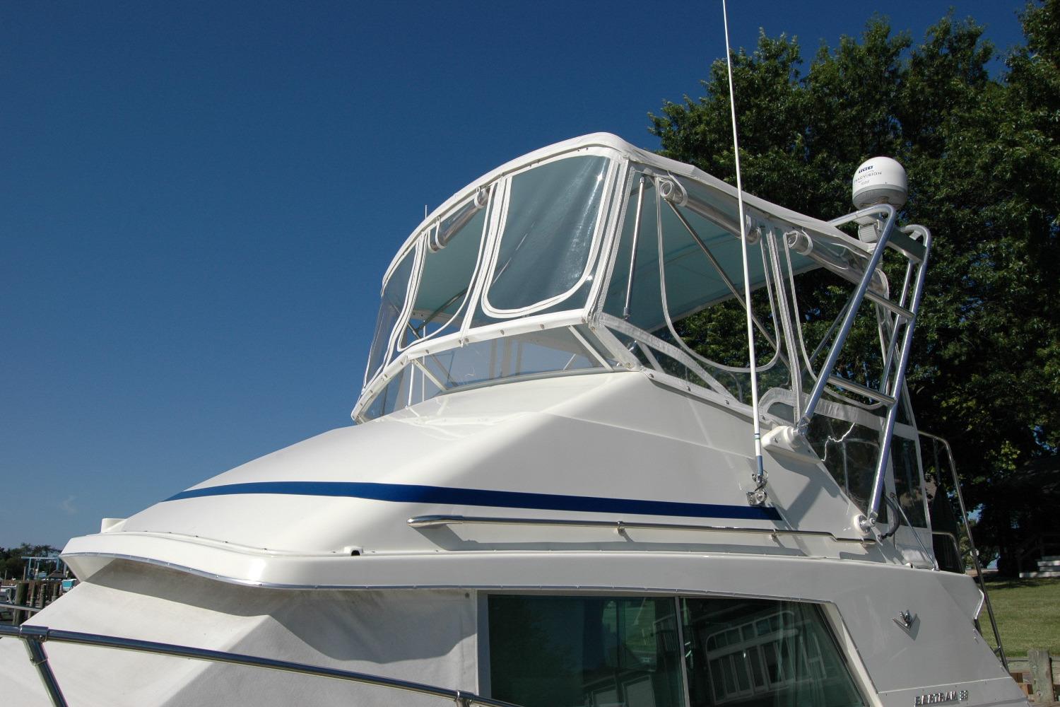 1987 Bertram 33 Sport Fisherman boat with blue accents under clear sky.