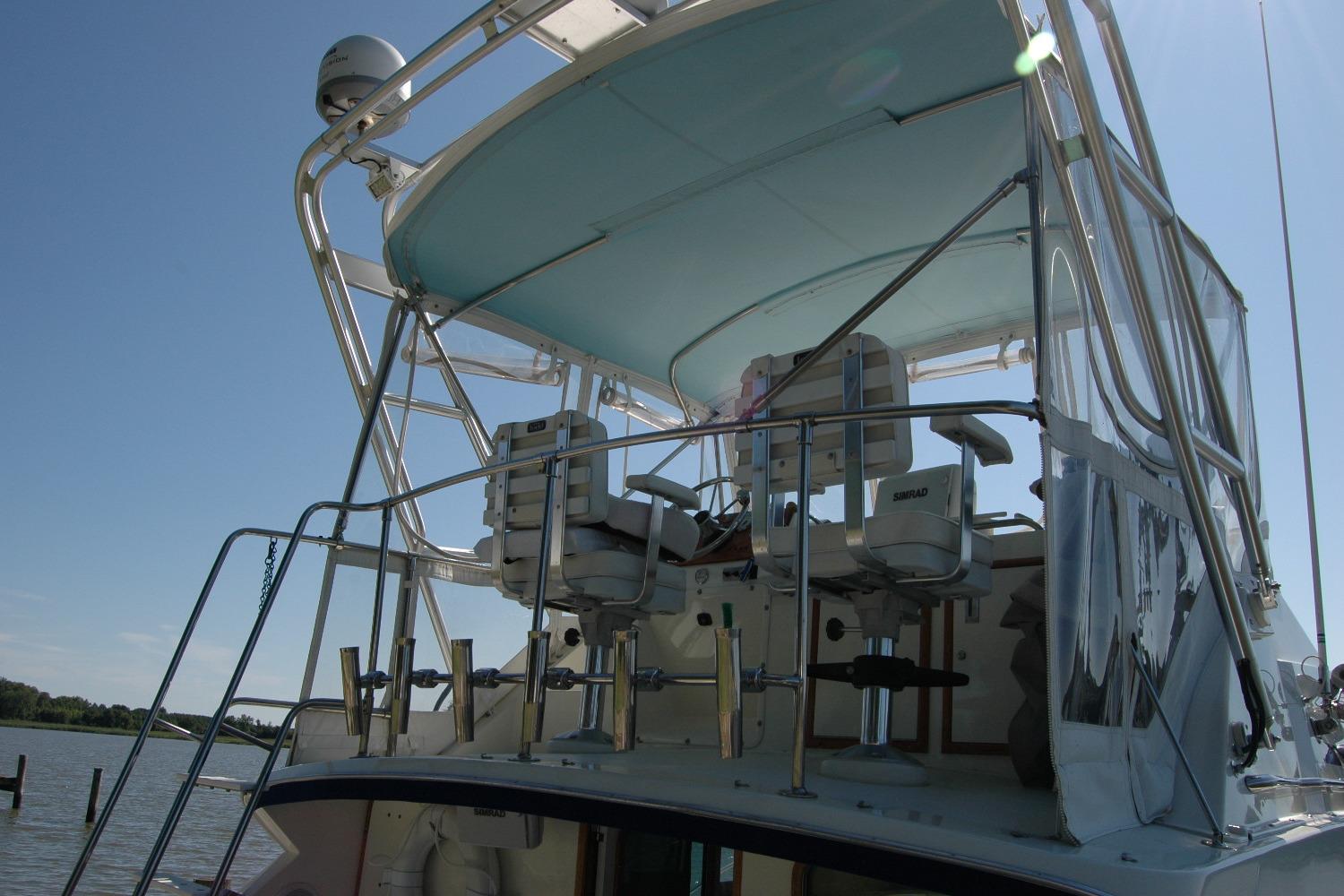 1987 Bertram 33 Sport Fisherman boat with upper deck seating and canopy.