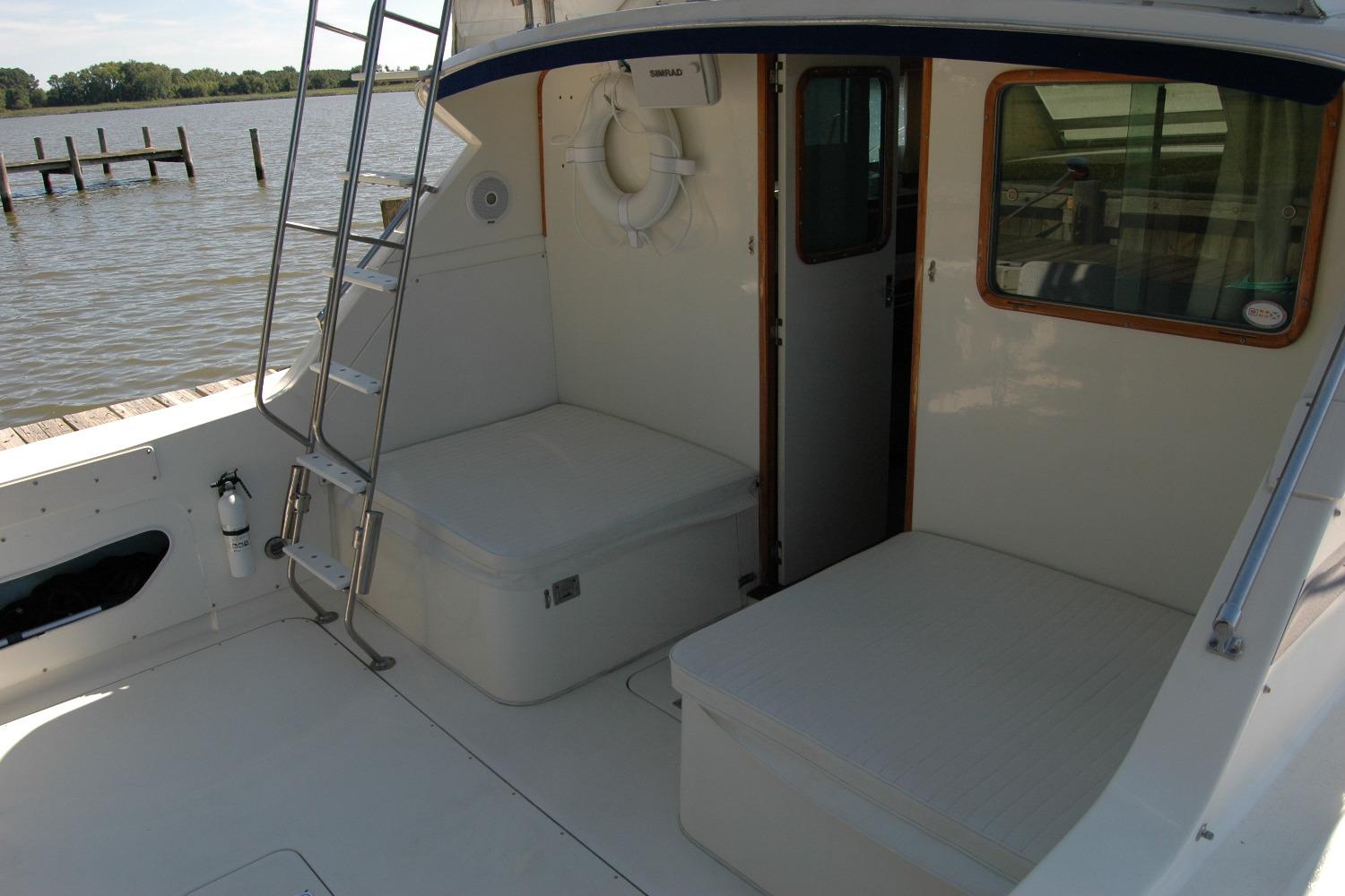 1987 Bertram 33 Sport Fisherman boat interior with seating and ladder by the water.