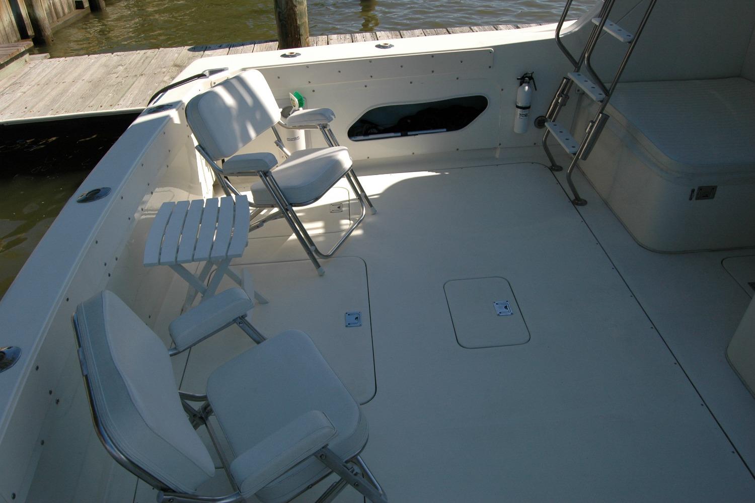 1987 Bertram 33 Sport Fisherman boat deck with chairs and table, docked by water.