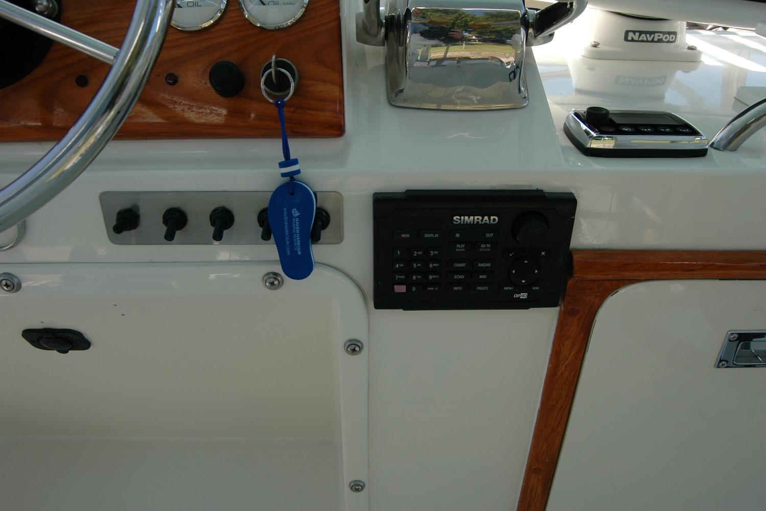 Control panel of a 1987 Bertram 33 Sport Fisherman with Simrad electronics and steering wheel.