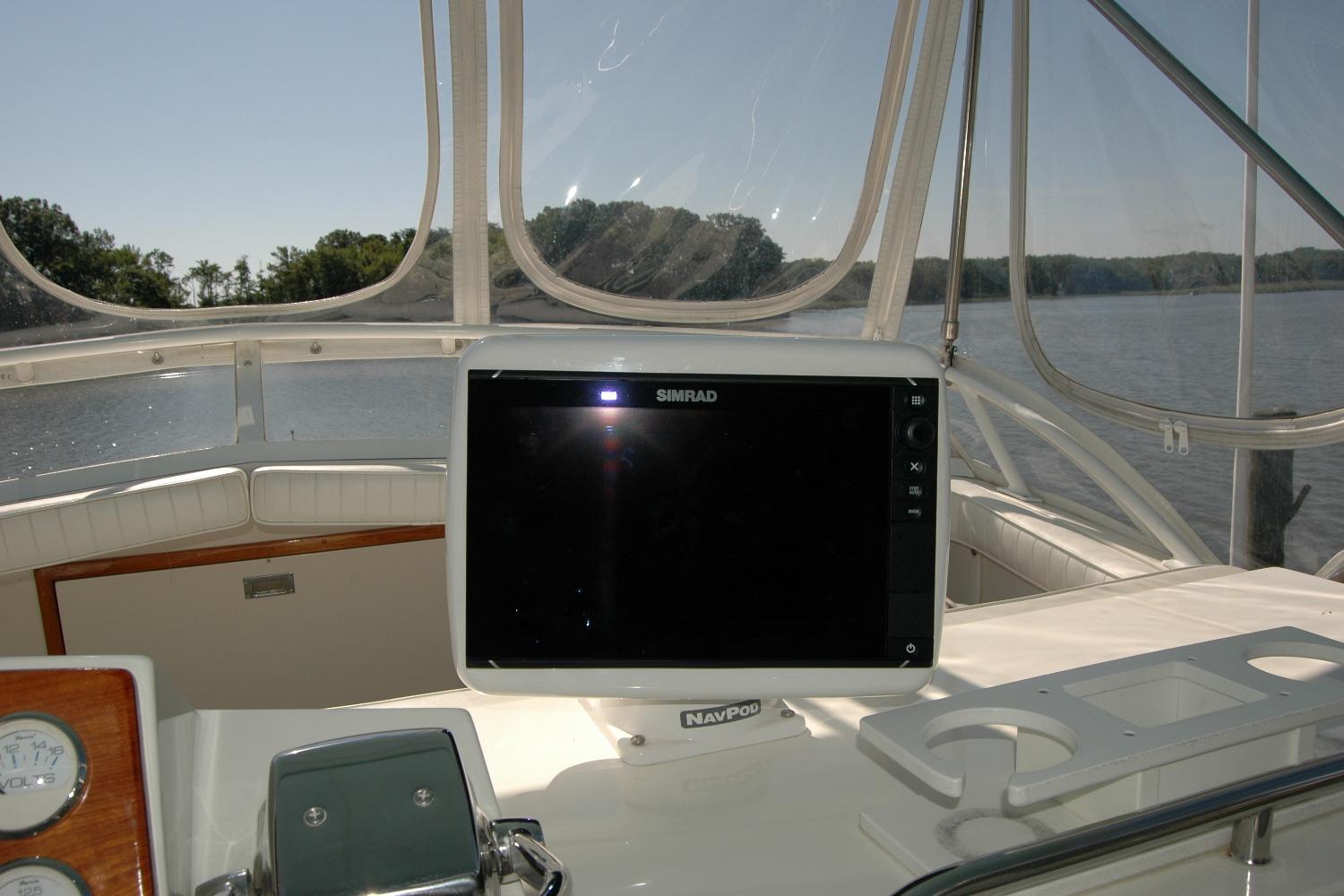 1987 Bertram 33 Sport Fisherman helm with Simrad navigation system, overlooking calm waters.