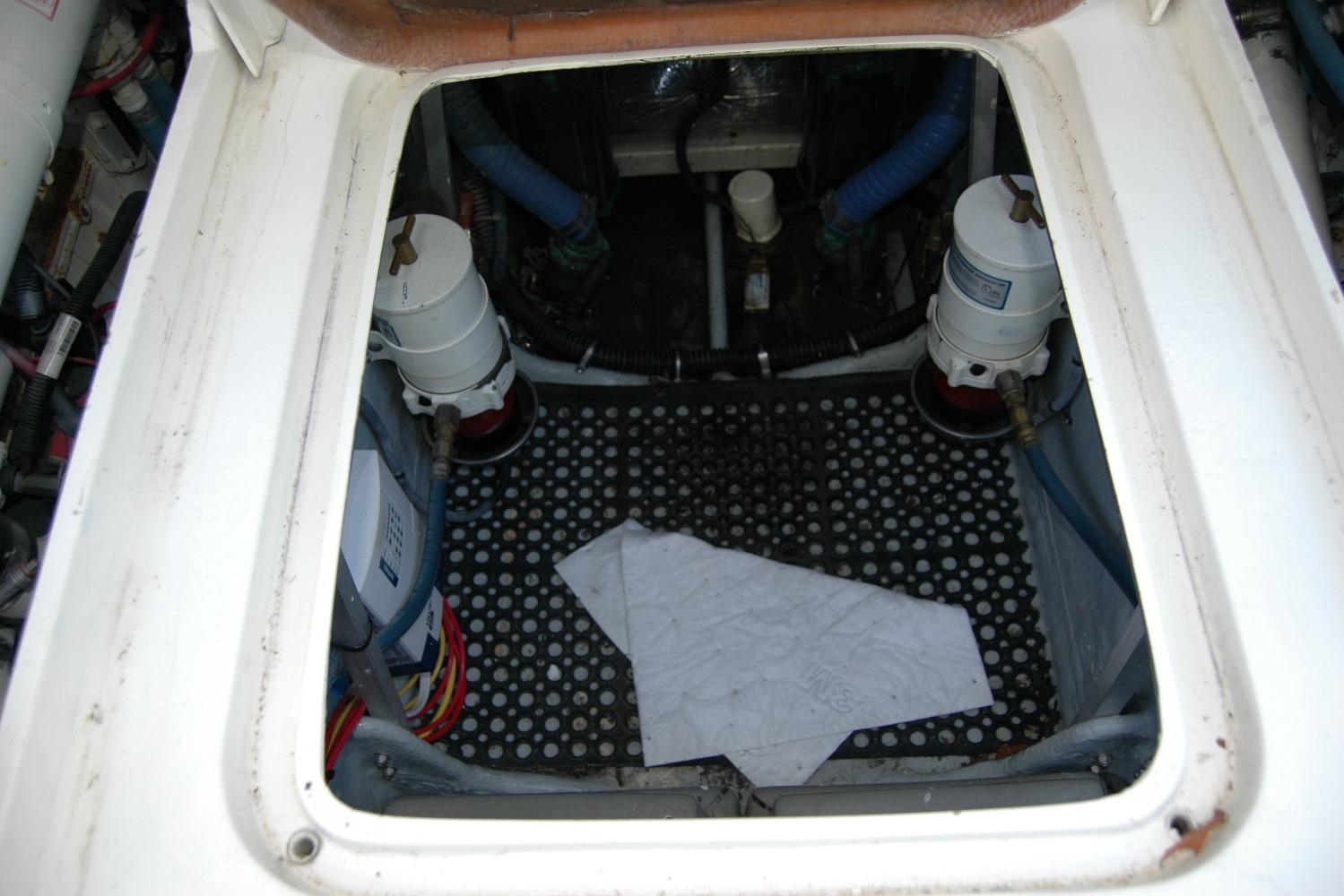 Engine compartment of a 1987 Bertram 33 Sport Fisherman boat, showing filters and hoses.
