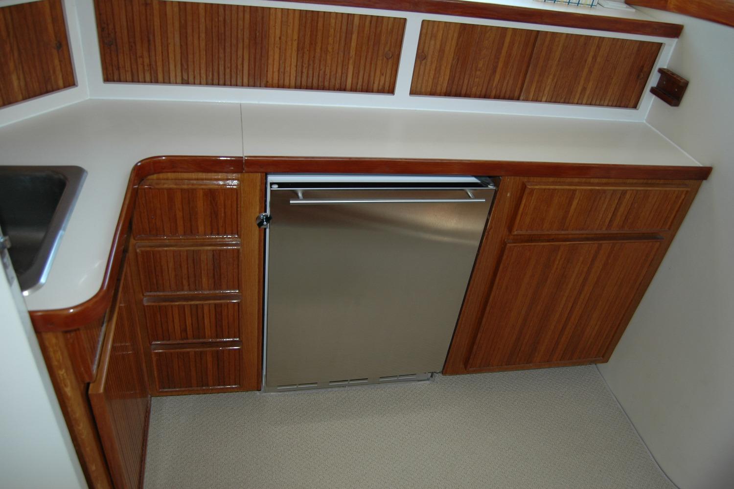1987 Bertram 33 Sport Fisherman galley with wood cabinetry and stainless steel appliances.